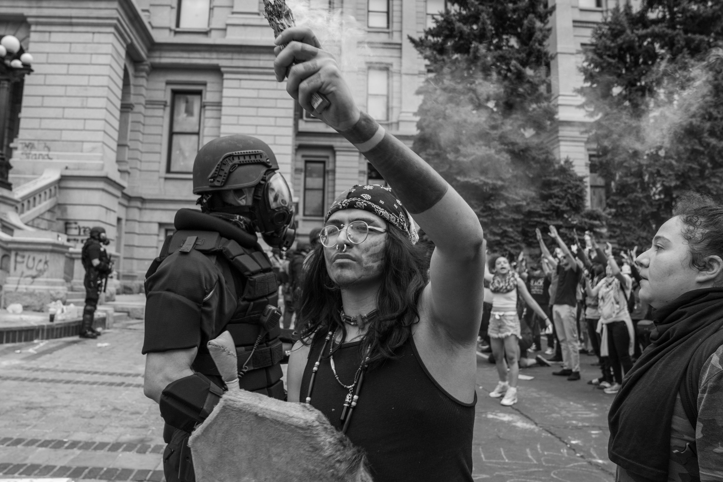 A protester holds a bundle of burning sage in the air. 5/30/2020.