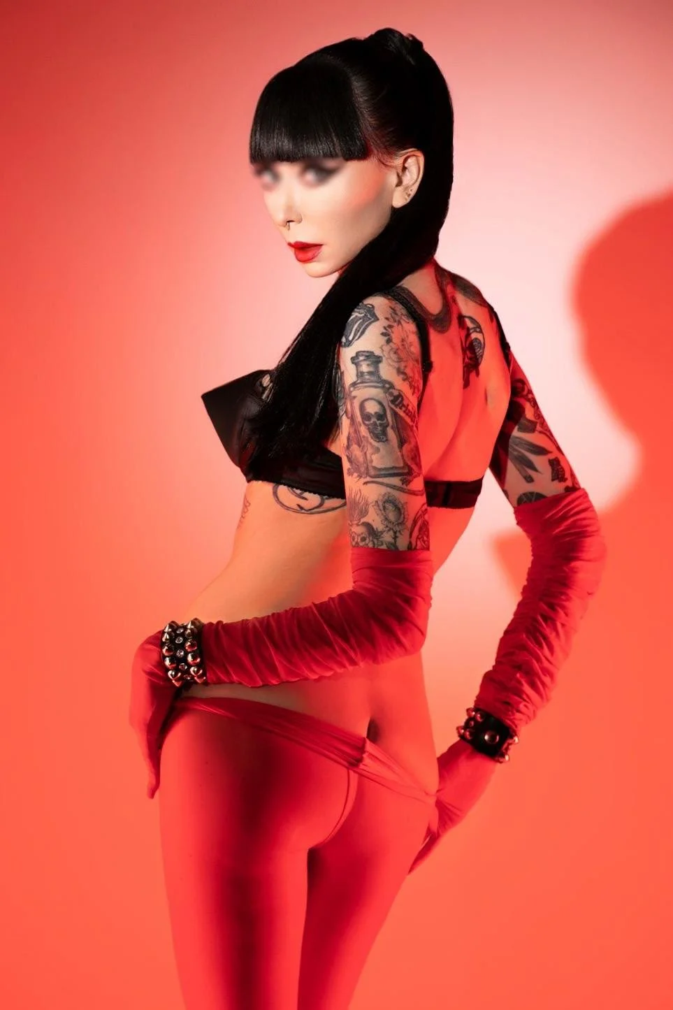 NYC Ramona Ryder is wearing a black bullet bra and red nylons with red opera gloves.