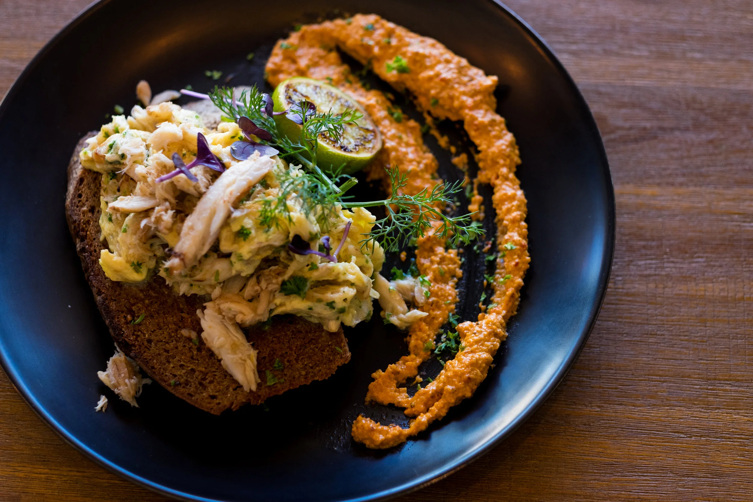 Scramble crab meat on dark rye bread with spicy romesco sauce