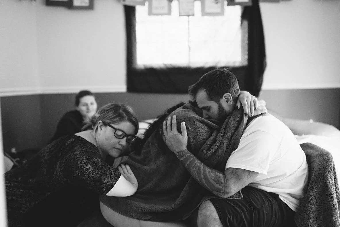 In questo parto in casa, la ostetrica preme sulla schiena della mamma per aiutarla a superare una contrazione (onda). Photo credit: Lauren Allmond Photography