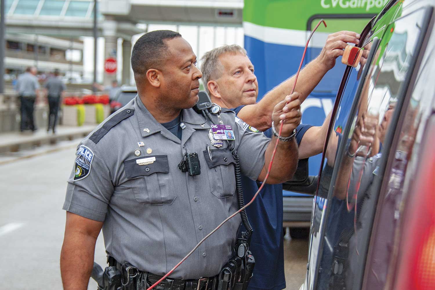  Cincinnati-Northern Kentucky International Airport Cpl. Calvin Gardner, left, helps a man unlock his van outside the main terminal. (Photo by Jim Robertson) 