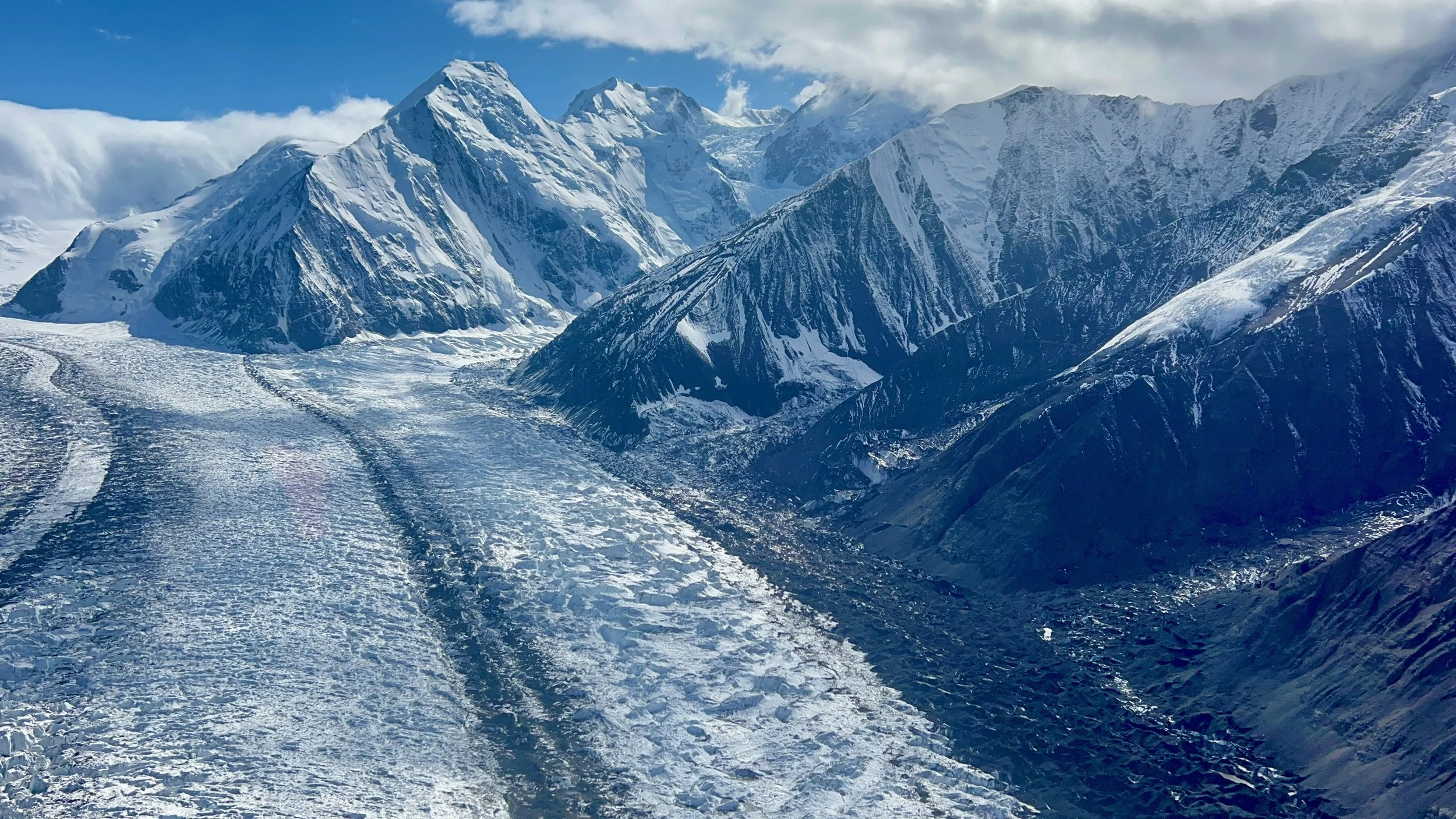 Snow-covered mountains with glaciers and cloudy sky.