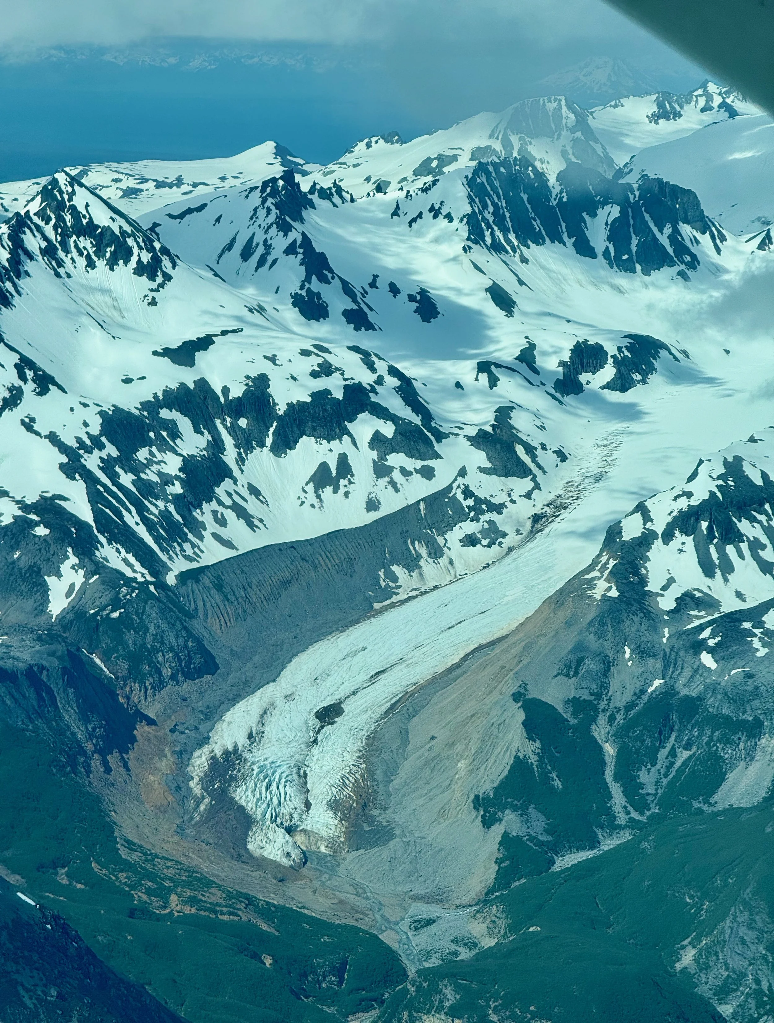 Aerial view of snow-covered mountains and glaciers with sharp peaks in a remote, rugged landscape.