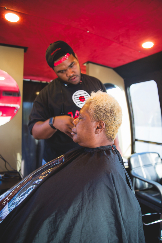 ABOVE: Javoris Brown gives Phyllis Williams a hair cut aboard the Love Beyond Walls bus — the same one Terence slept on top of to raise awareness about homelessness. The bus now travels the city, providing a welcome one-stop shop for hygiene for underserved people and those living on the streets.