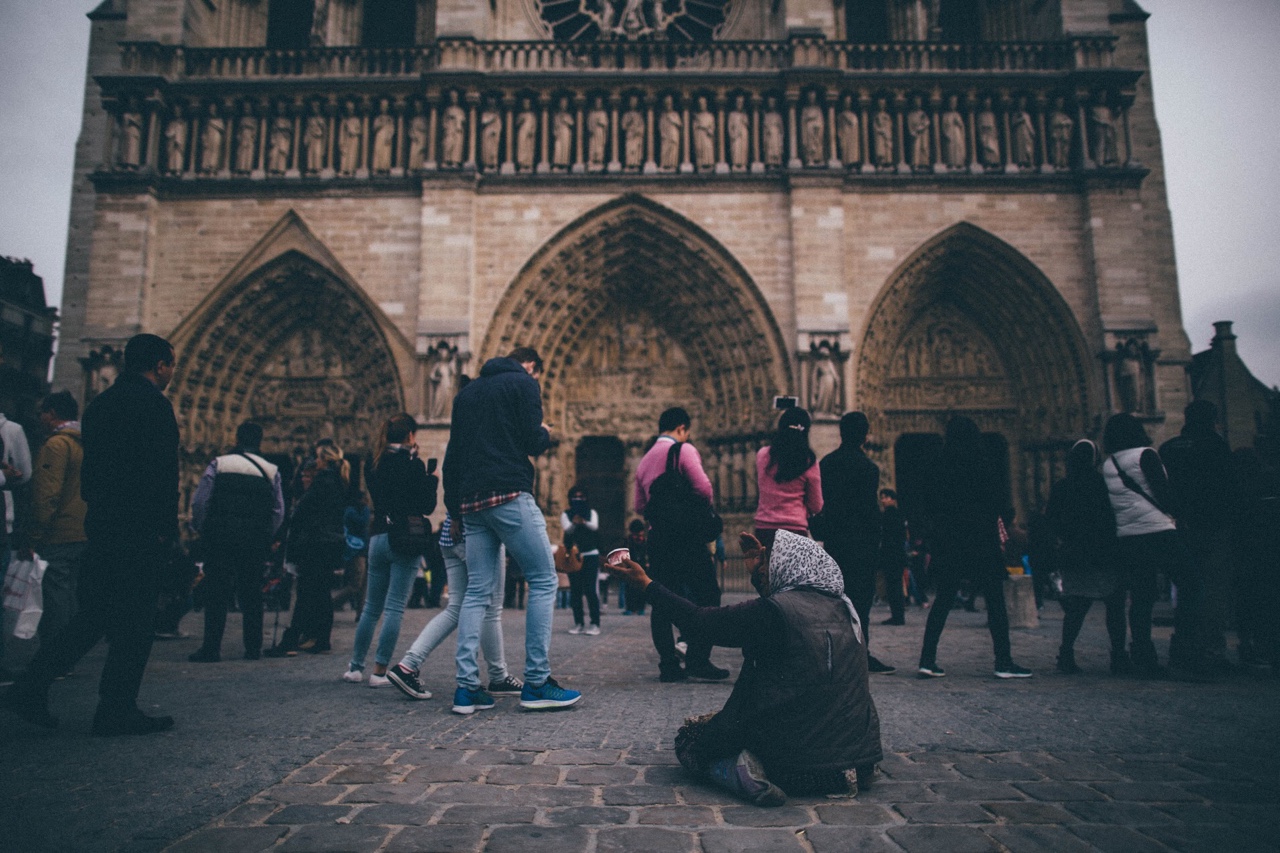   A woman begs for change as tourists wait to enter the Notre Dame Cathedral in the  fourth arrondissement. Paris, France   