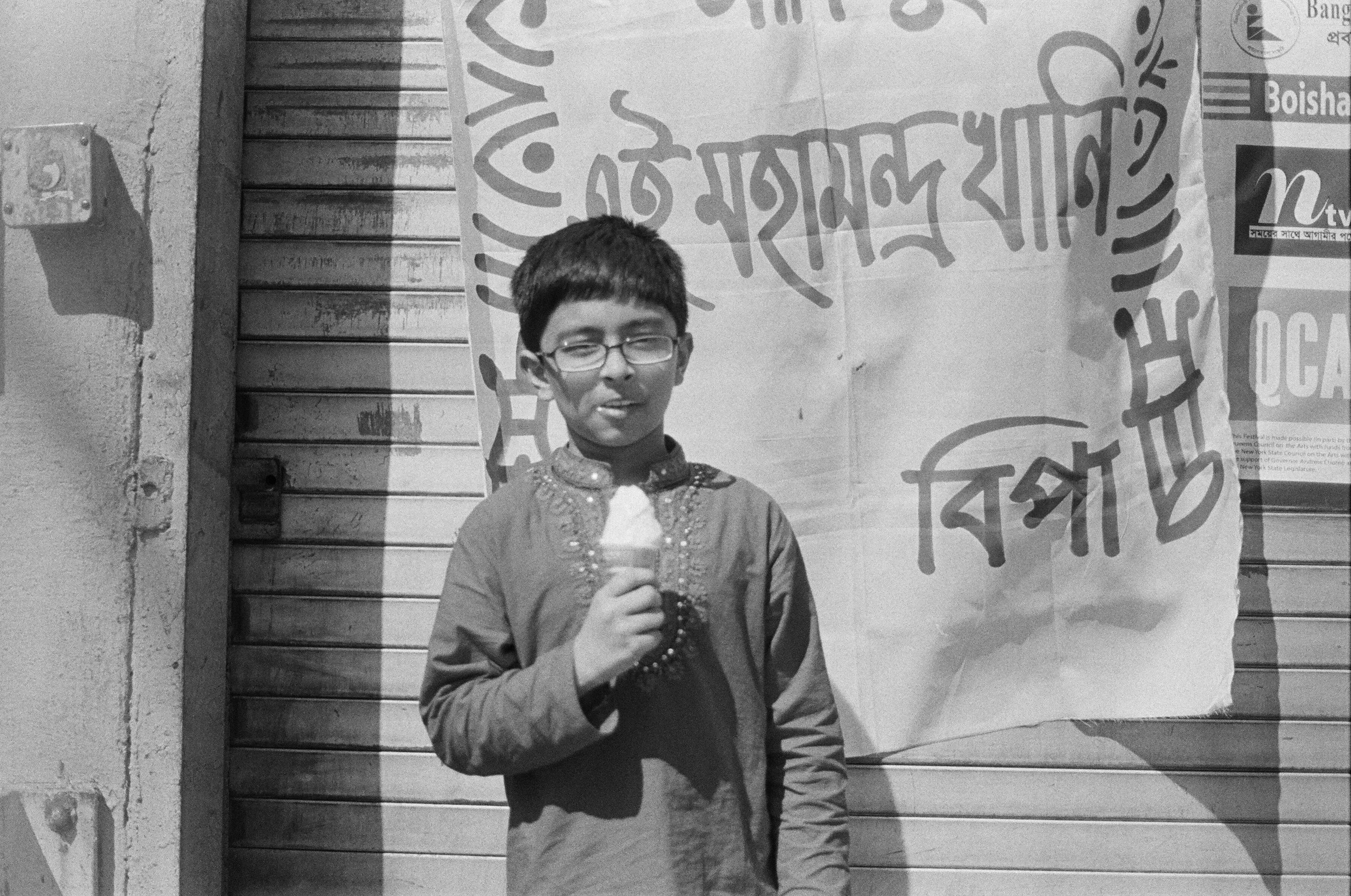   A young boy eats an ice cream cone during a Bengali day celebration.  