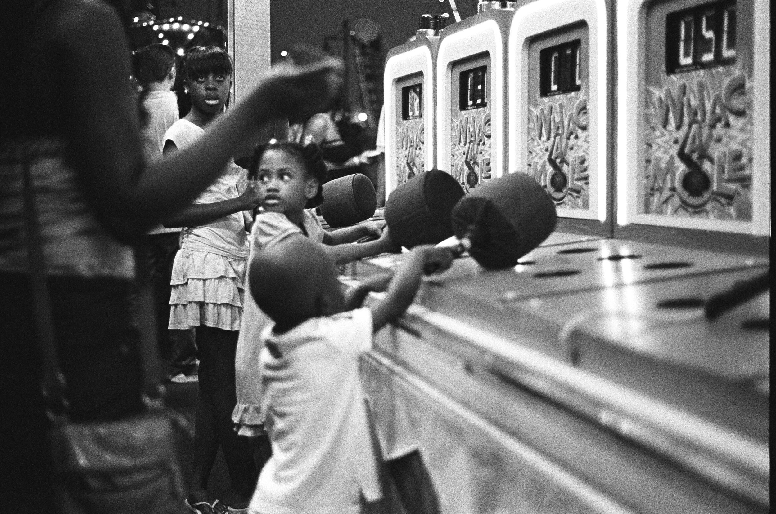   Siblings play Whack-A-Mole during a summer evening at Coney Island.&nbsp;  