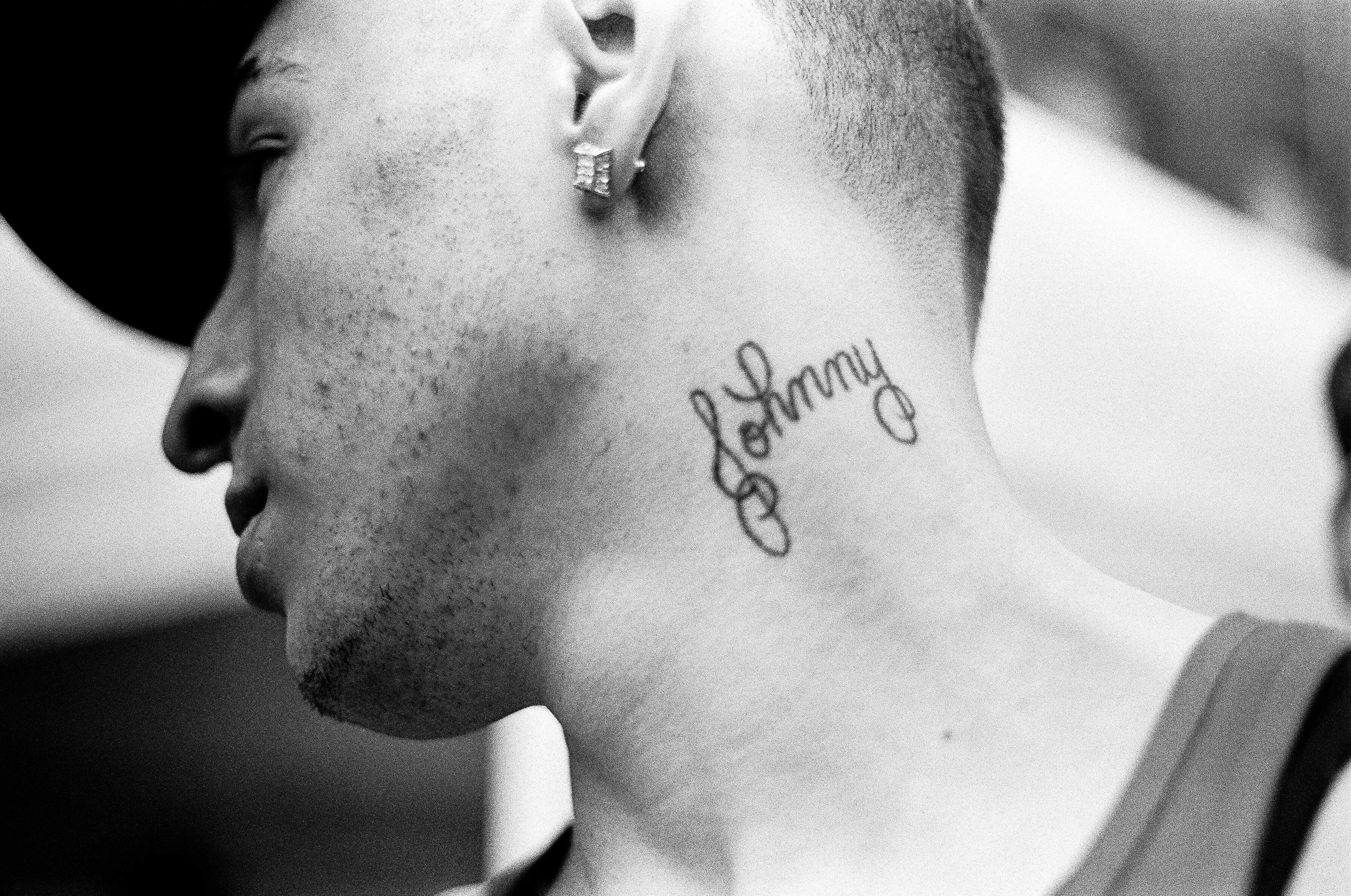   A young man shows off a neck tattoo that reads "Johnny"&nbsp;  