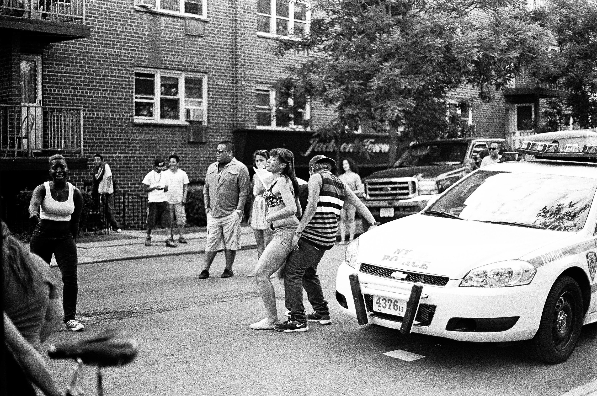   Teenagers dance on a NYPD car during a block party in Queens   