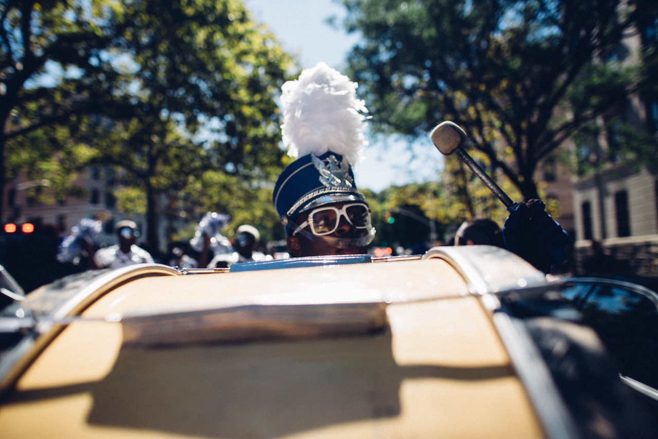   Marching band bass drummer keeps the beat for his group as they head uptown on Malcom X Boulevard. Harlem, New York.&nbsp;  