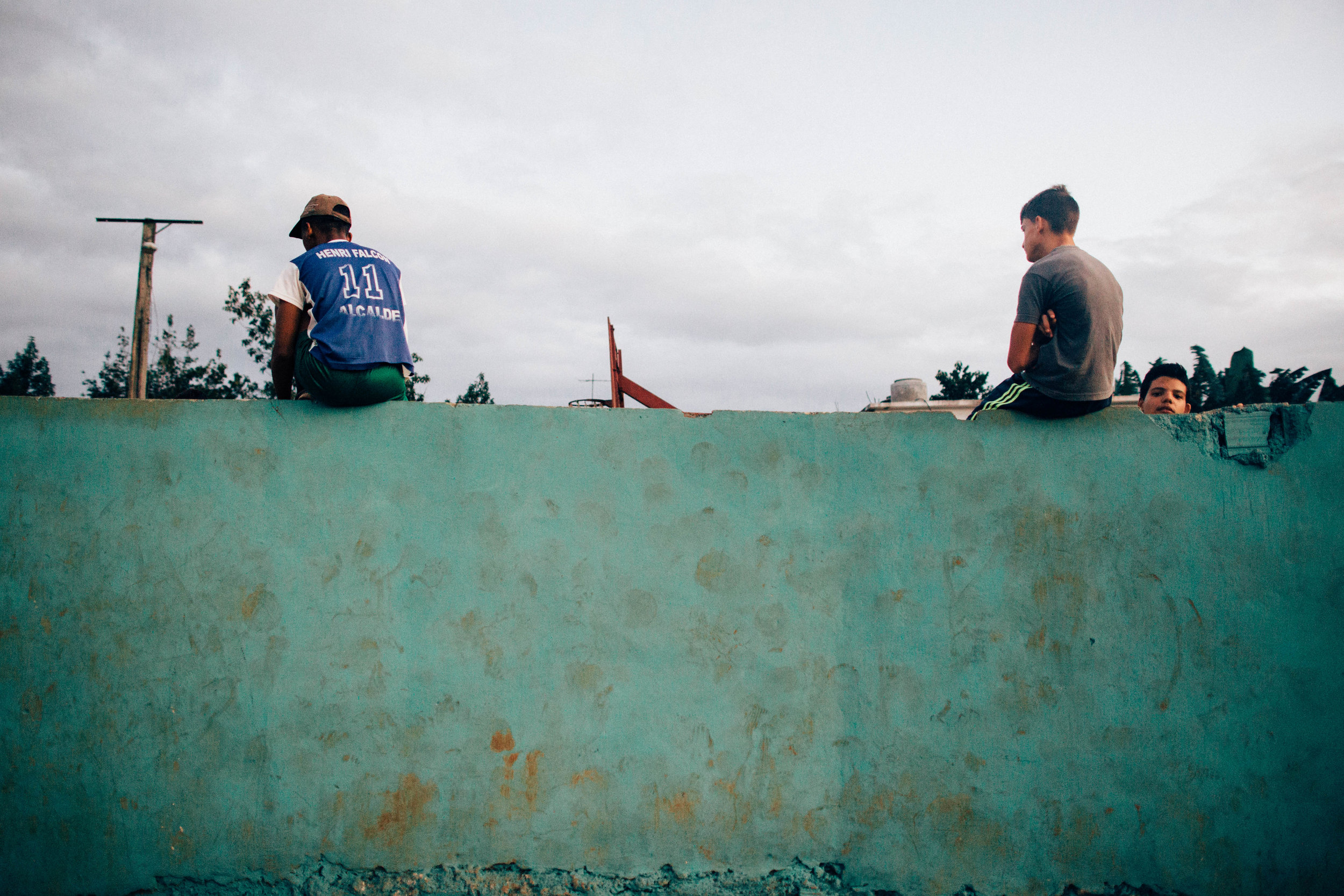   Three boys watch a basketball game at a neighborhood court.&nbsp;Viñales, Cuba.  