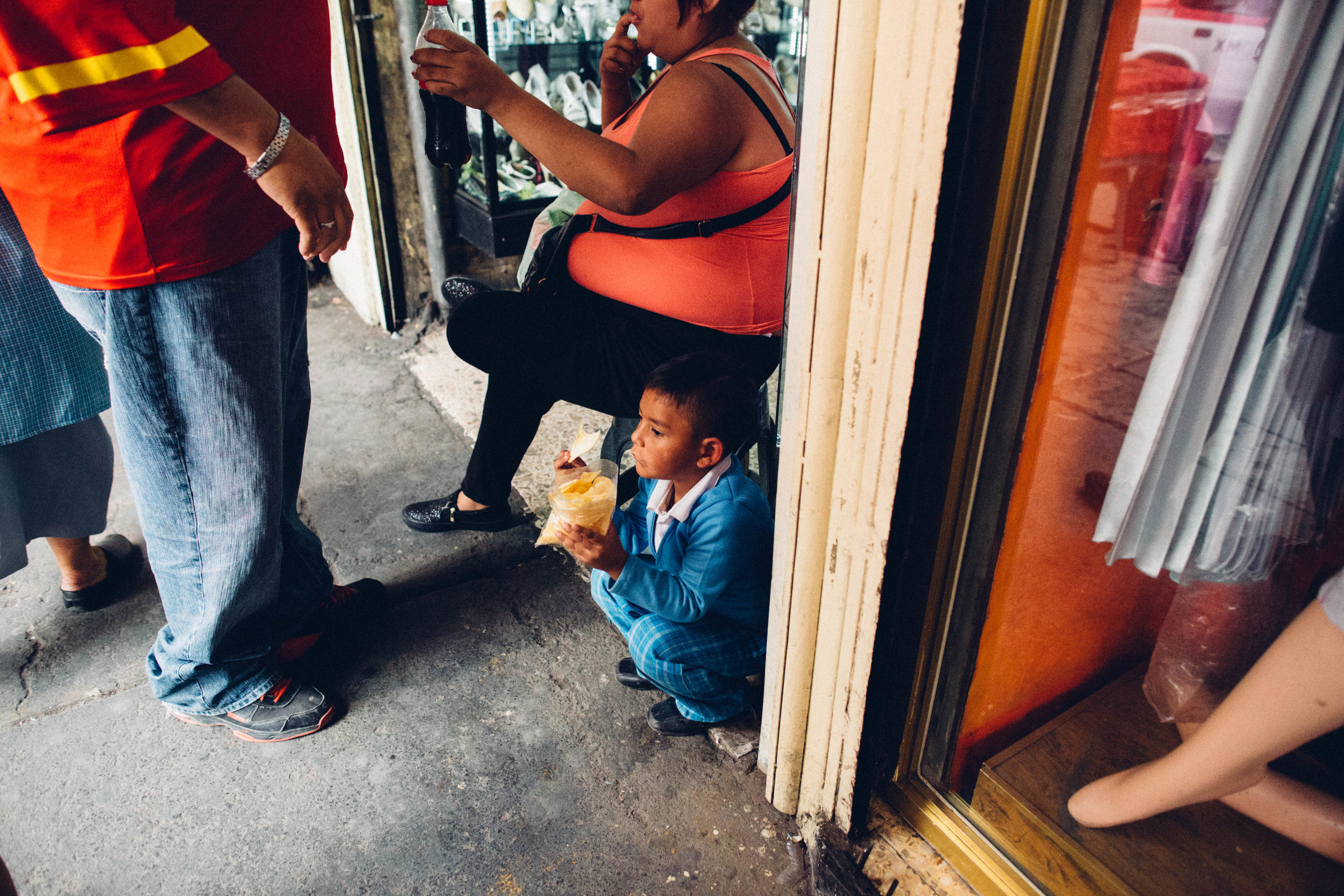   A young boy eats a snack near La Lagunilla market. Mexico City, Mexico.  