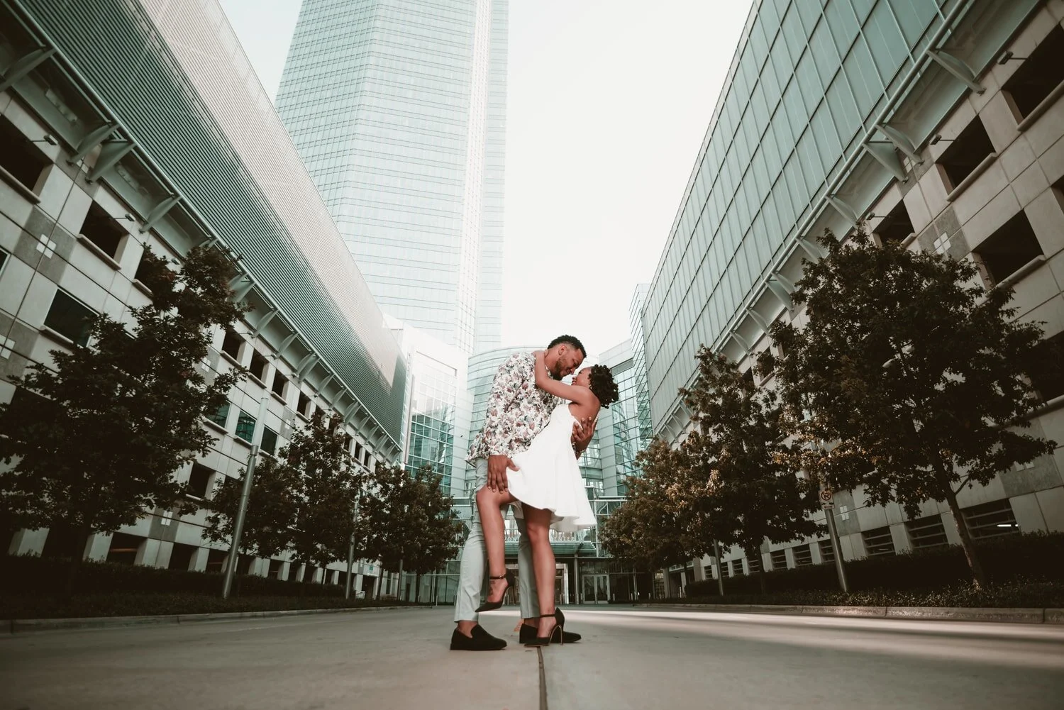 engagement-couple-dip-kiss-downtown-okc-buildings-trees.jpg