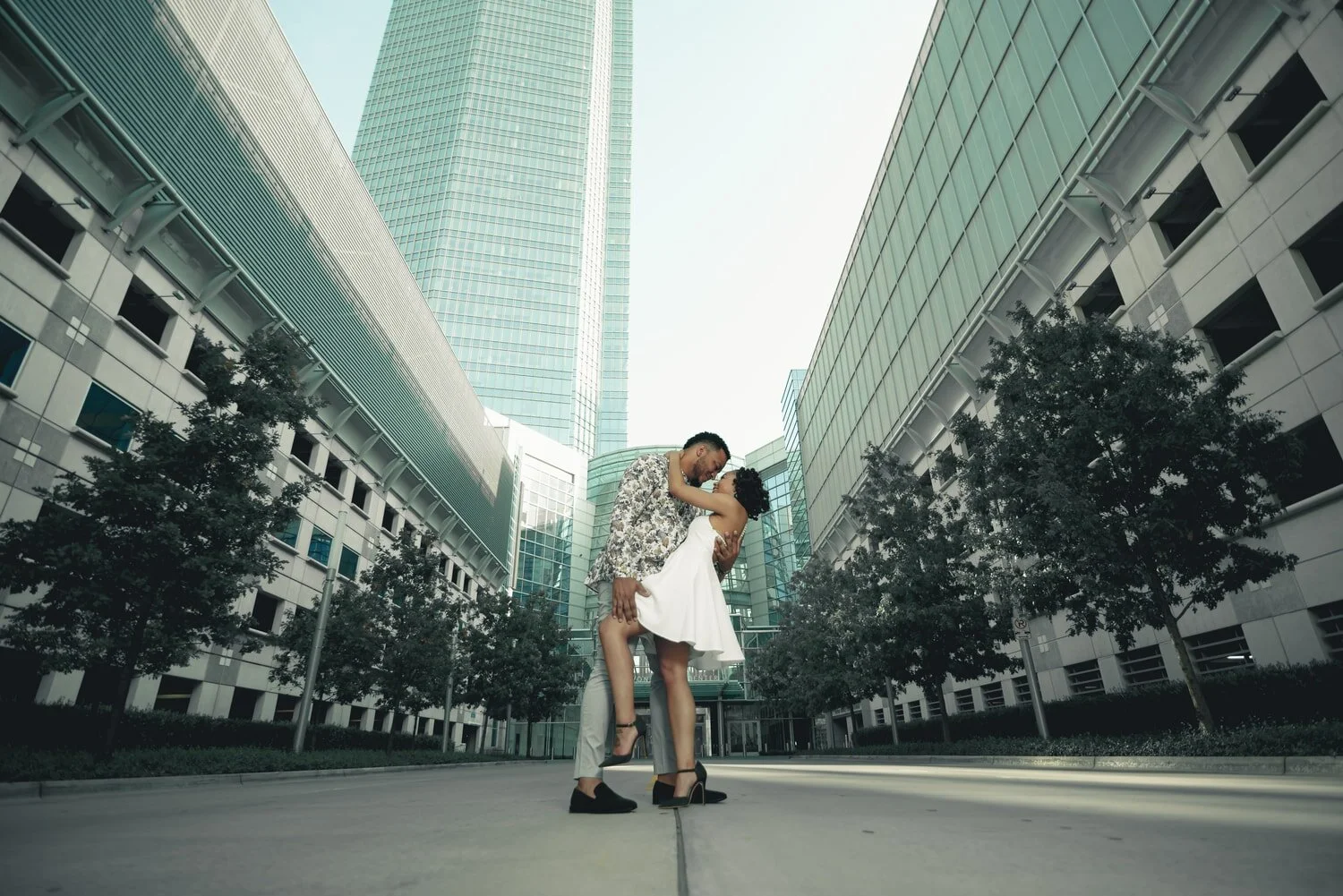engagement-couple-dip-kiss-downtown-okc-buildings-trees.jpg