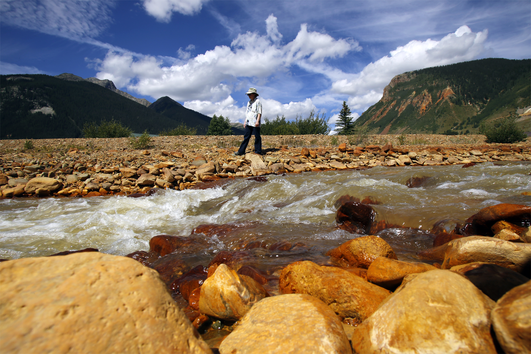 Melanie Bergolc, a resident of Silverton, Colo., walks along the banks of Cement Creek in Silverton, Colo on Aug. 10, 2015 where residue from the Gold King Mine spill is evident. 