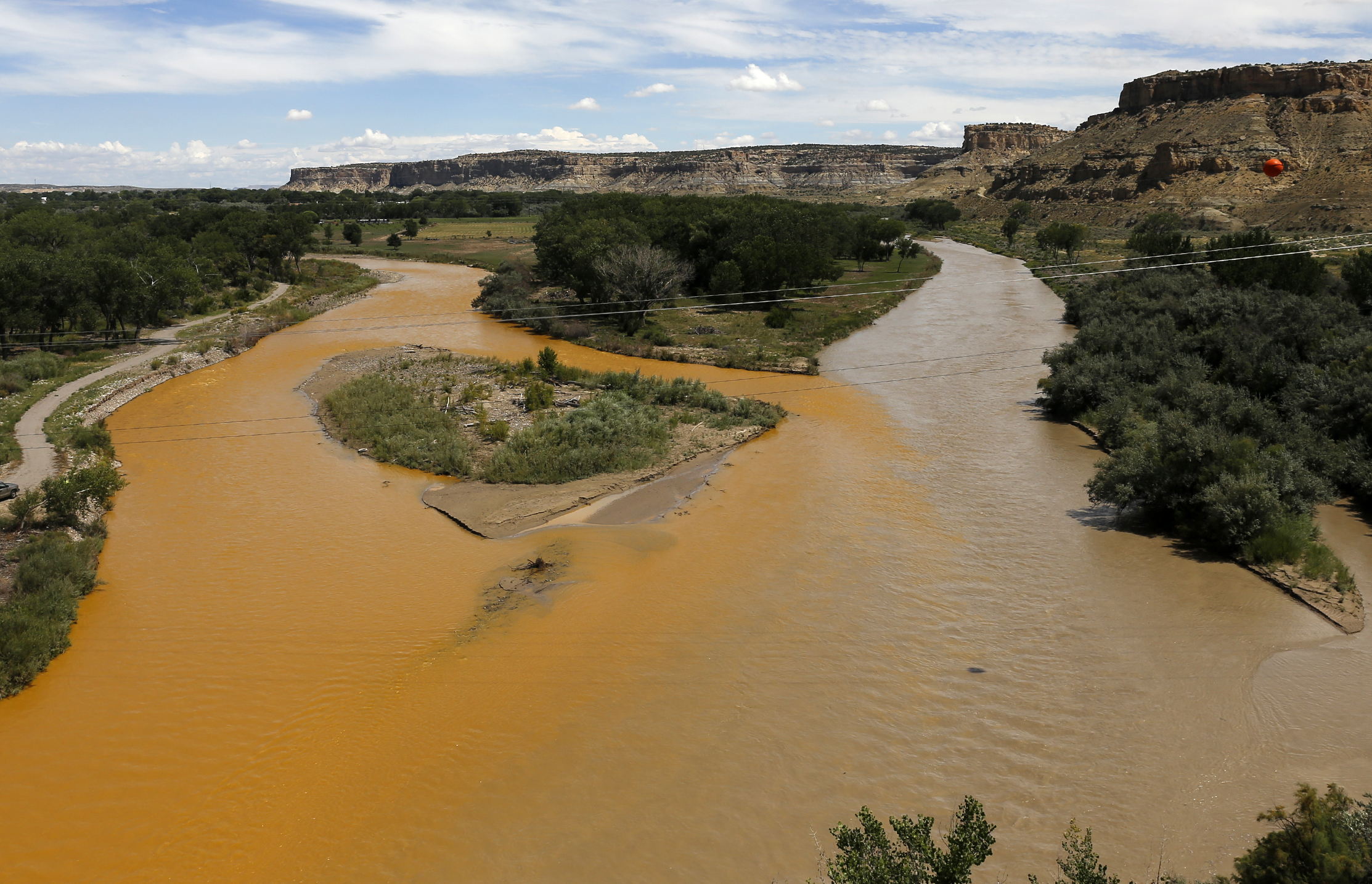 A plume of orange mine waste flows from the Animas River, left, and into the San Juan River, right, pictured Aug. 8, 2015 at the river's confluence in Farmington, New Mexico. 