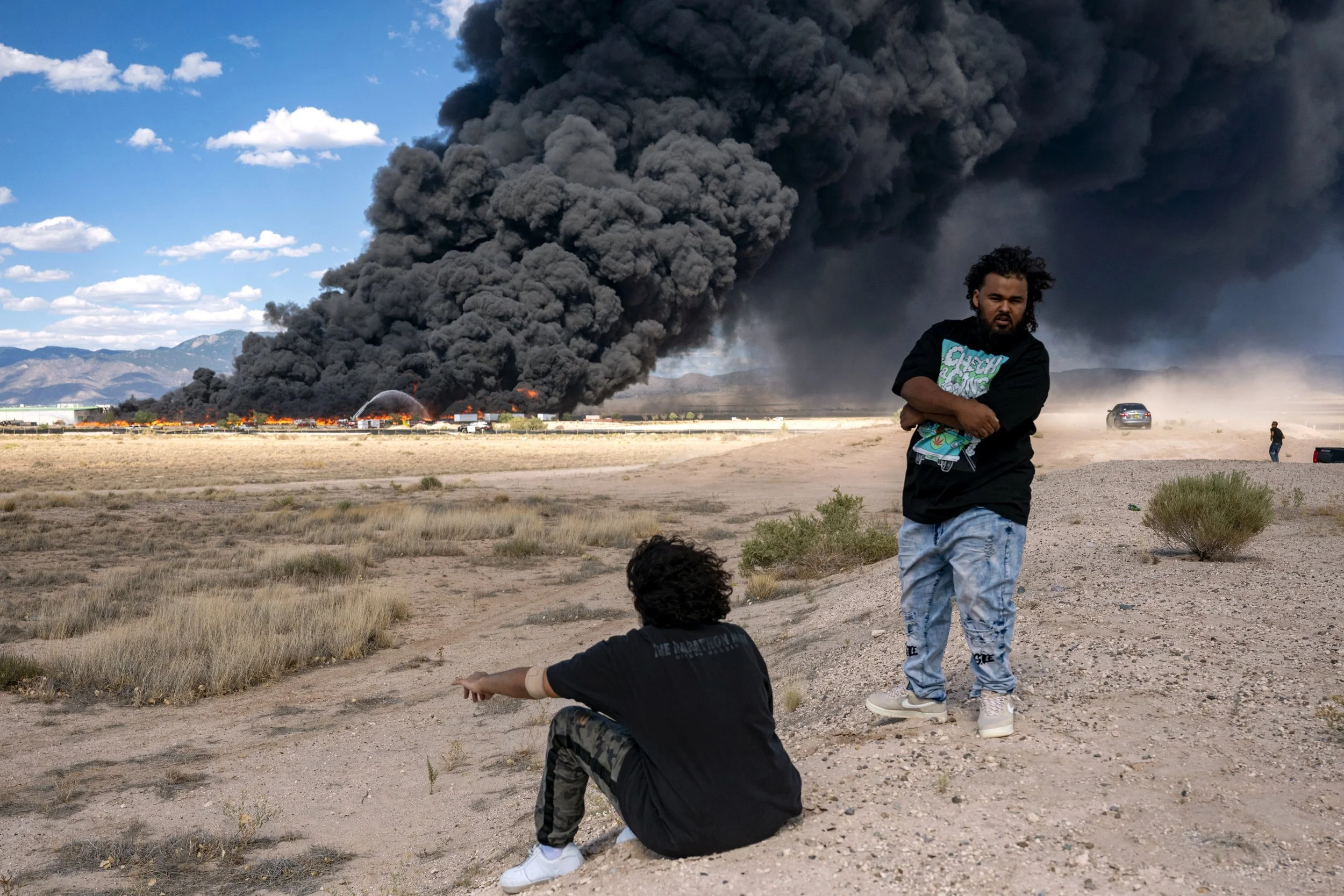  Albuquerque residents watch as firefighters battle a large commercial fire at a plastic storage facility in Mesa Del Sol, southeast of Albuquerque on Sunday, Aug. 6, 2023.  