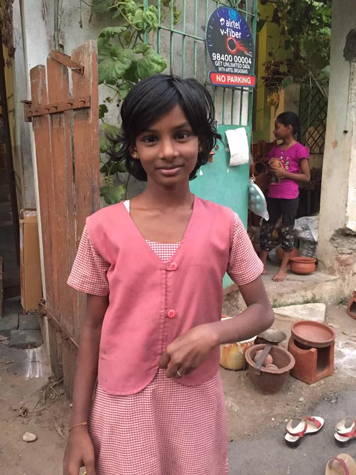 This sweet girl asked me to take her photo on my way home from school. She's wearing a school uniform. On the ground behind her you can see some terra cotta pots. The one with the gap on the front of it and the bowl on top is where a traditional Pongal food is made. They cook rice, lentils, milk, and sugar in the bowl over a fire made with wood. They intentionally let the milk overflow as a symbol of abundance. What a nice tradition! :)