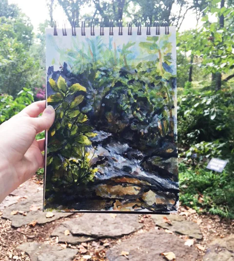 My painting of the stream held up against the forest background. ©2016 by Erin Blumer.