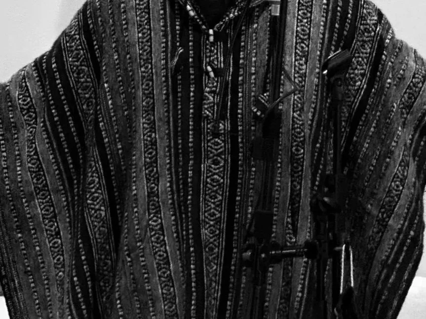 Close-up of a patterned, striped shirt with sunglasses hanging from the collar.