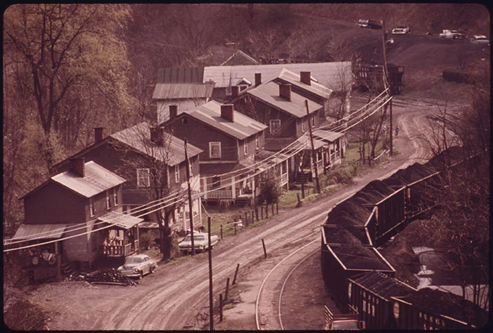 Caption: Closeup of an old coal company mining town of Red Ash Virginia. This is a classic picture of a company town with a railroad in the valley flanked by miners homes. These houses are two family dwellings; the road is made of red dog, a mining byproduct. Photographer: Jack Corn Date Created: 1974 April