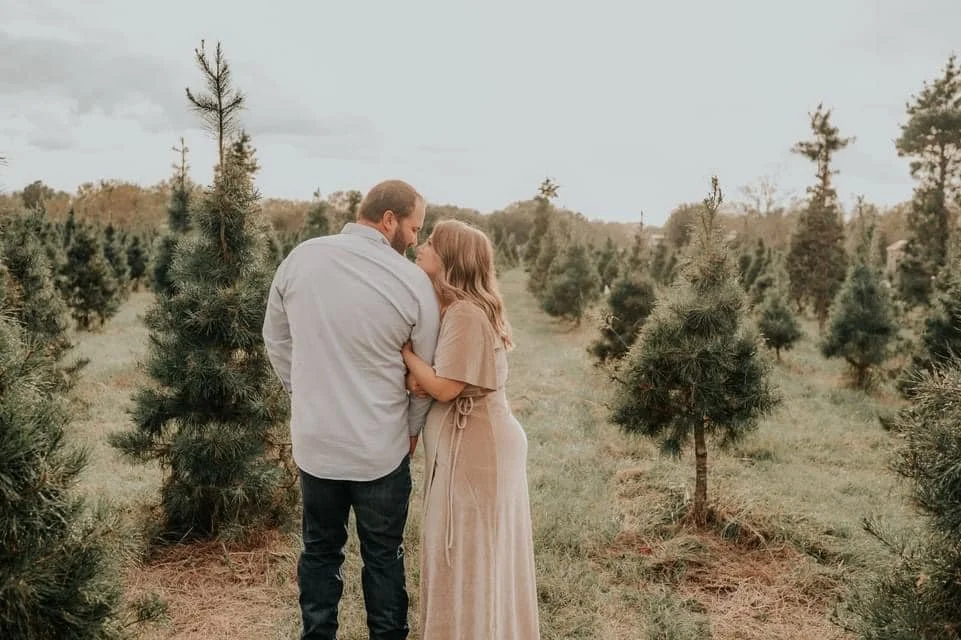 Couple snuggling in Christmas trees