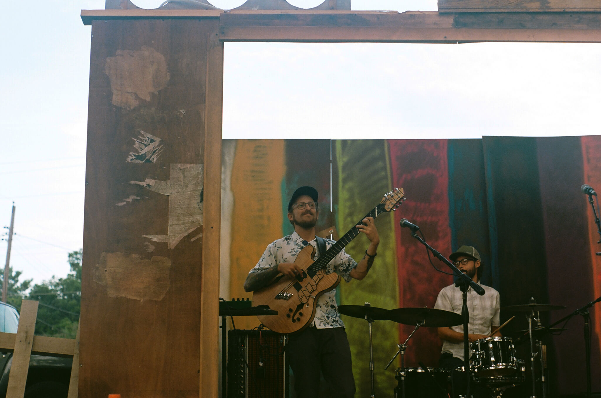 Eli Kahn performing with Tom Nania and Arthur Schroeder as AIRIAR inside the TV set built by Lauren Steinhofer and Jay Jeffcoat .