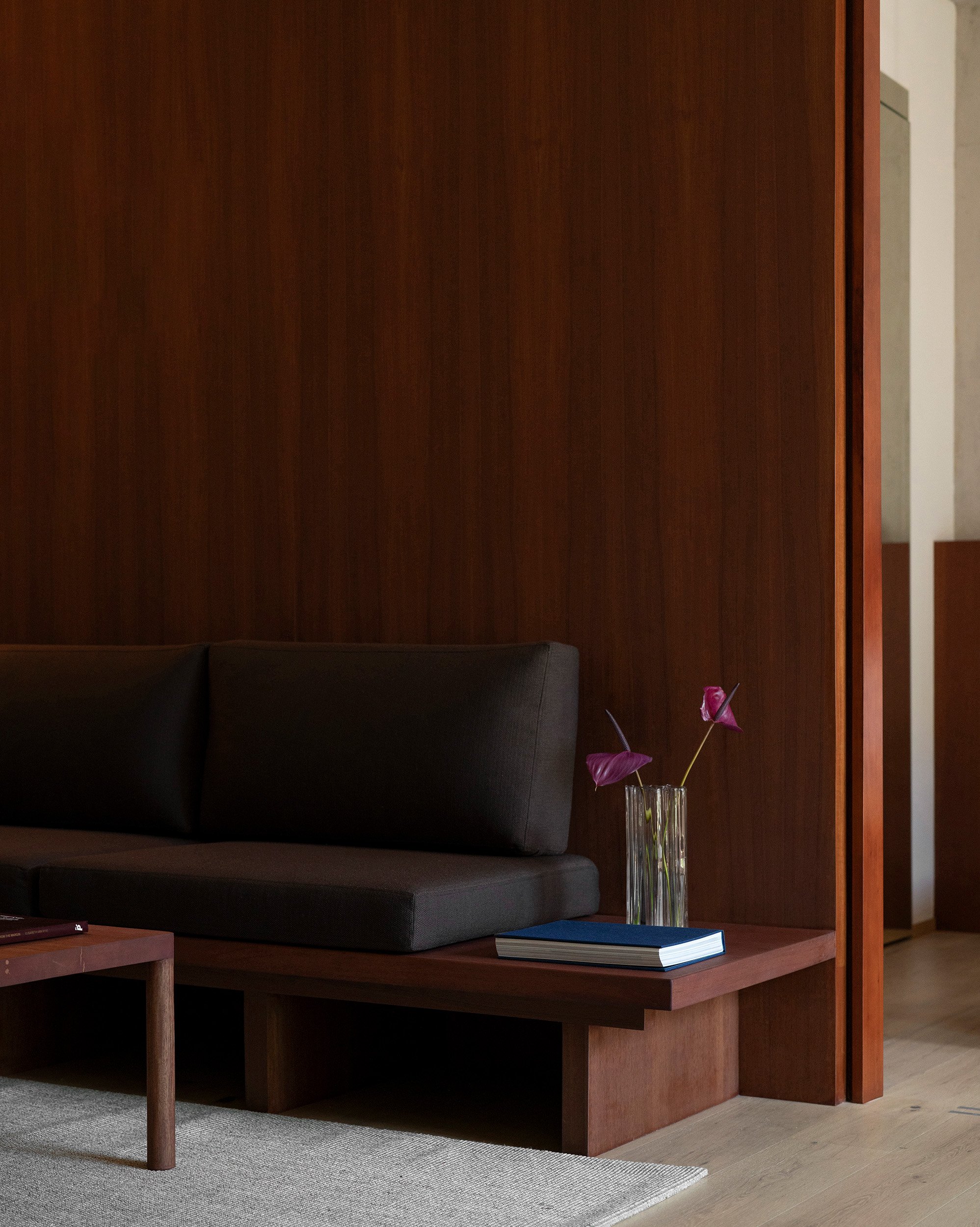 Detail view of custom built-in wooden bench base with dark upholstery and integrated ledge at San Luis apartment in Mexico City, interior design by Mariel Lozano Studio, photo by Fabian Martinez.