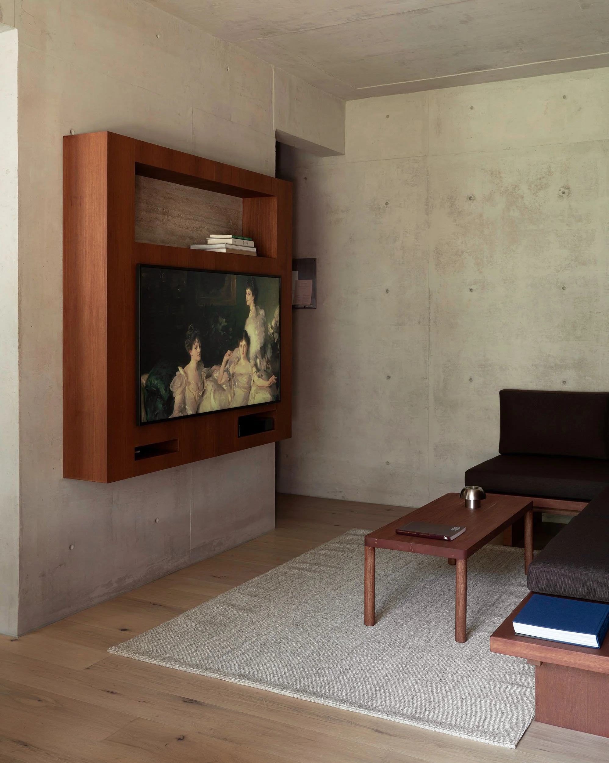Custom wall-mounted timber TV enclosure set against board-formed concrete walls at San Luis Airbnb in Mexico City, interior design by Mariel Lozano Studio, photo by Fabian Martinez.