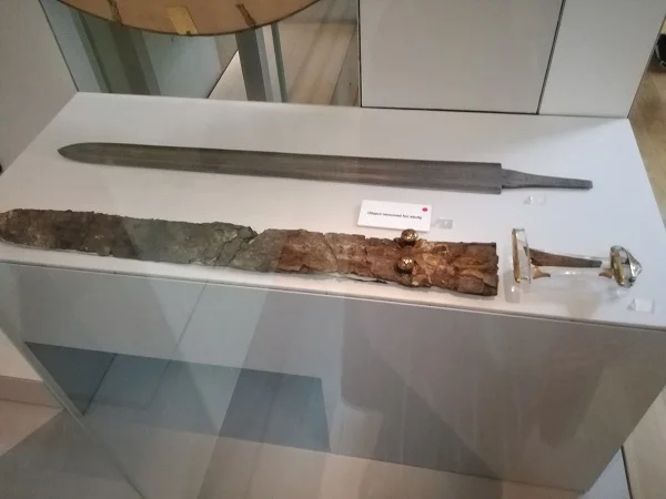 Double-edged sword – “In early Anglo-Saxon England swords were the most prized weapons of all, given as gifts by lords and passed on as heirlooms. The Sutton Hoo sword is the finest known from the period. The double-edged iron blade was fitted with gold hilt (handle) pieces. They are decorated with garnets imported from southern Asia, set into gold cells (cloisonné). It was buried in a wooden leather-bound scabbard, lined with wool to keep the blade bright.” (permanent display)