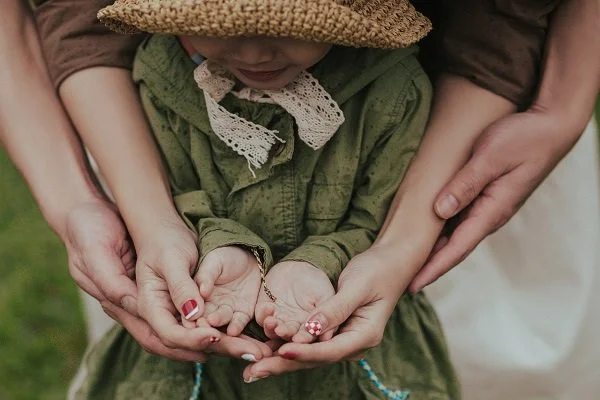 little girl, green dress, straw hat, hands, mother's hands, father's hands