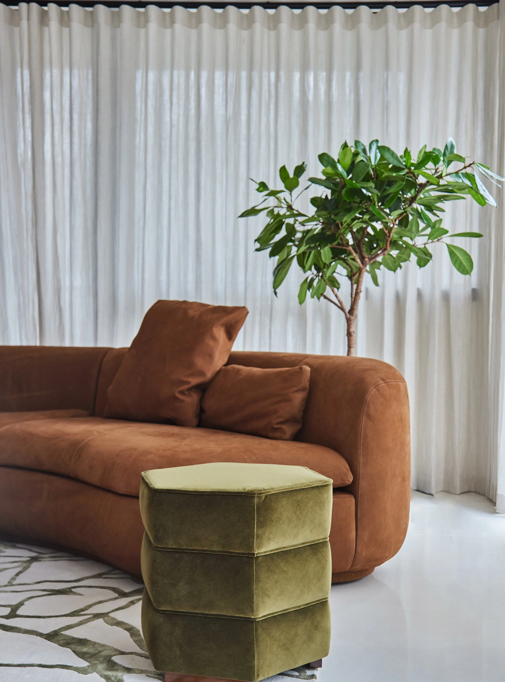 Calm-Mayfair-retreat-_0016_Modern-curved-sofa-green-velvet-ottoman-sheer-drapes.jpg