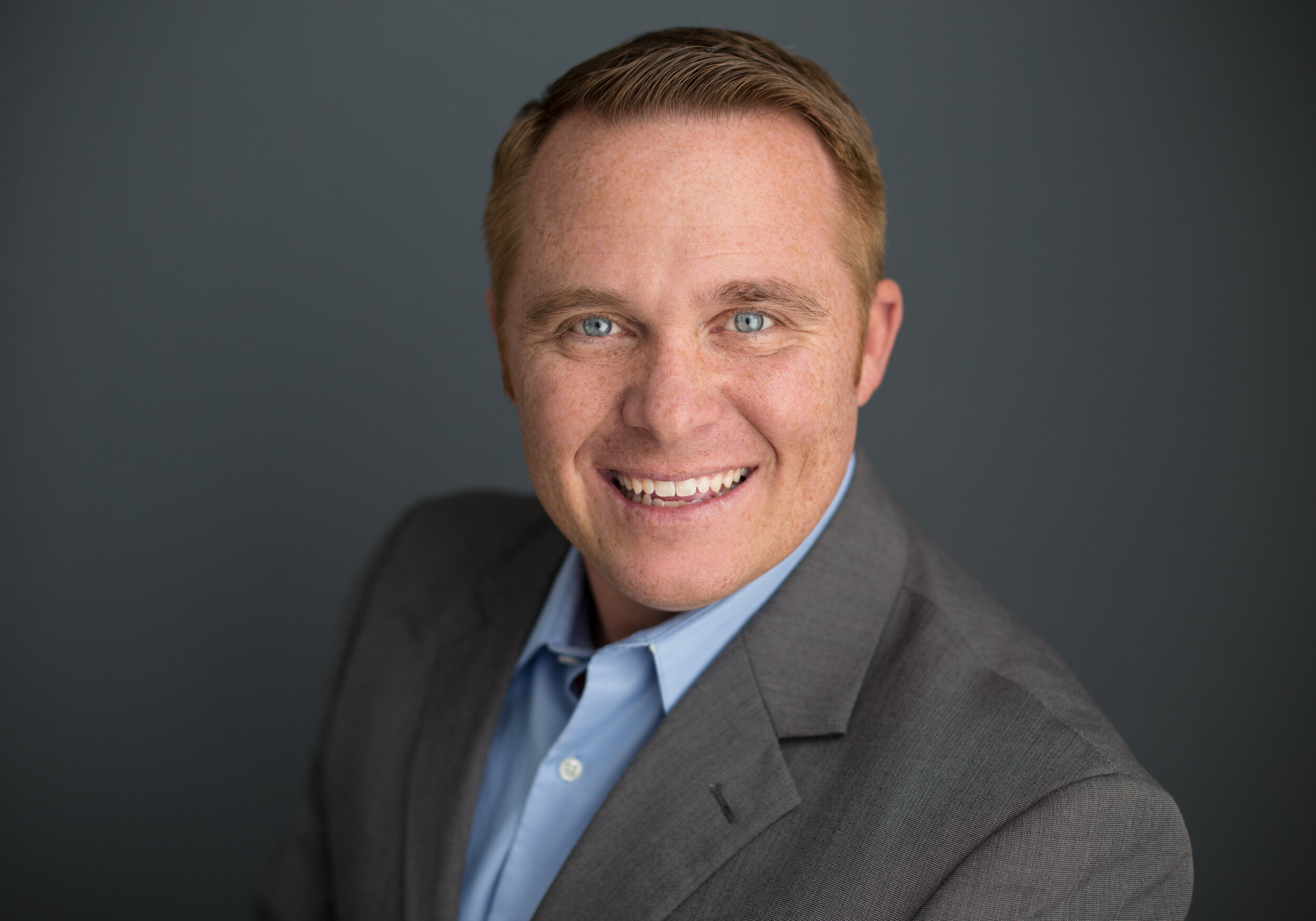 Smiling man in a suit against a dark background