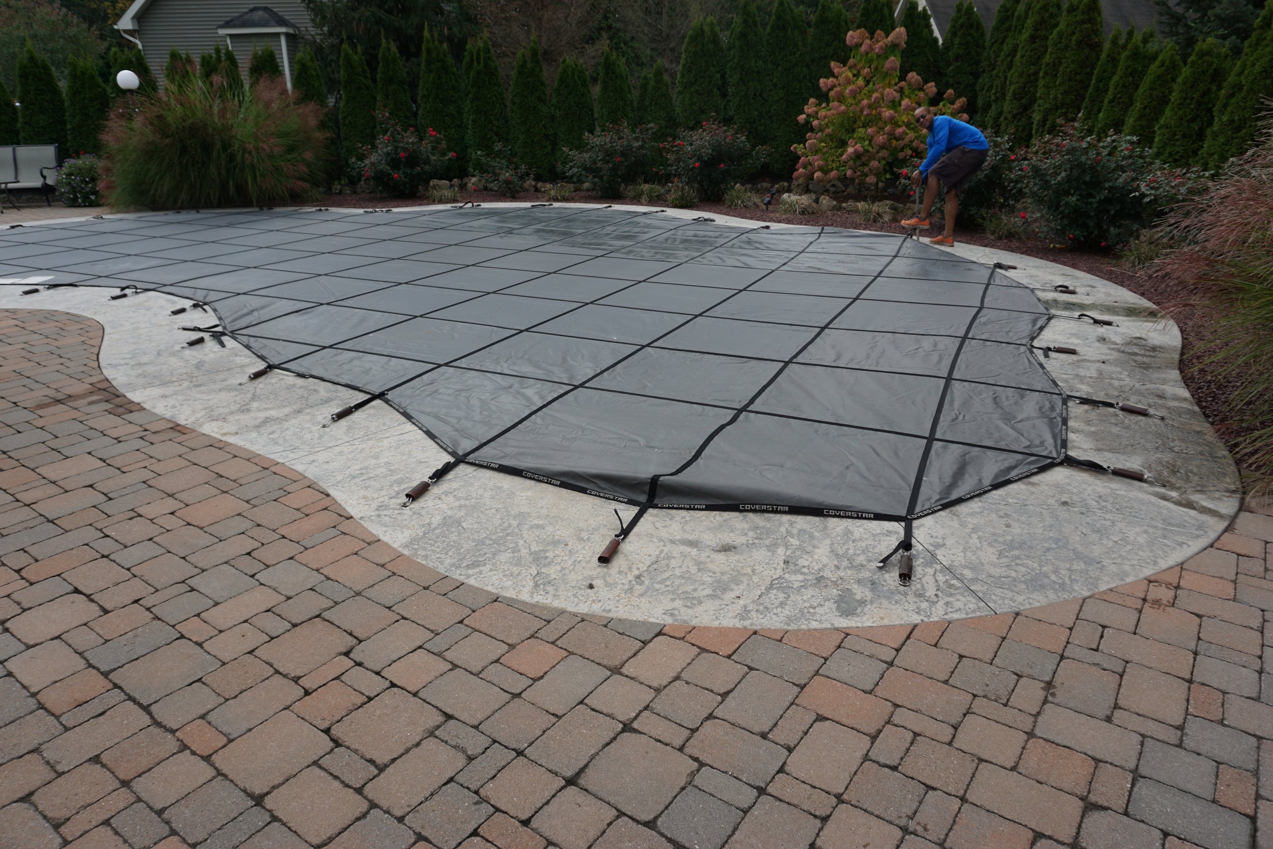 Professional spring pool opening service in a Webster, NY neighborhood. The Handy Family team performing a safety cover removal and initial debris clearing for a residential inground pool.