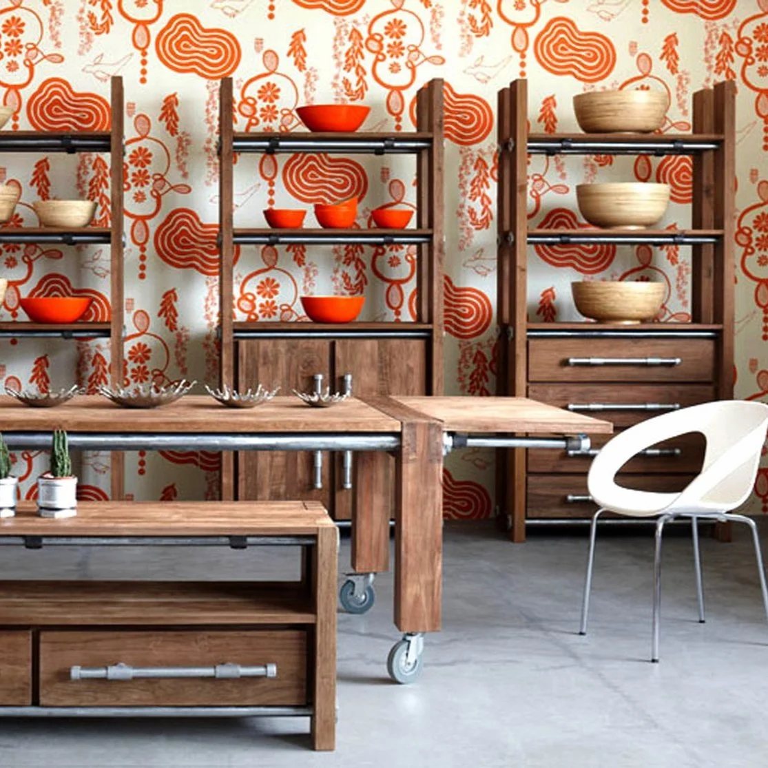 Interior space with wooden furniture, shelves with bowls, and a patterned orange and white wallpaper.
