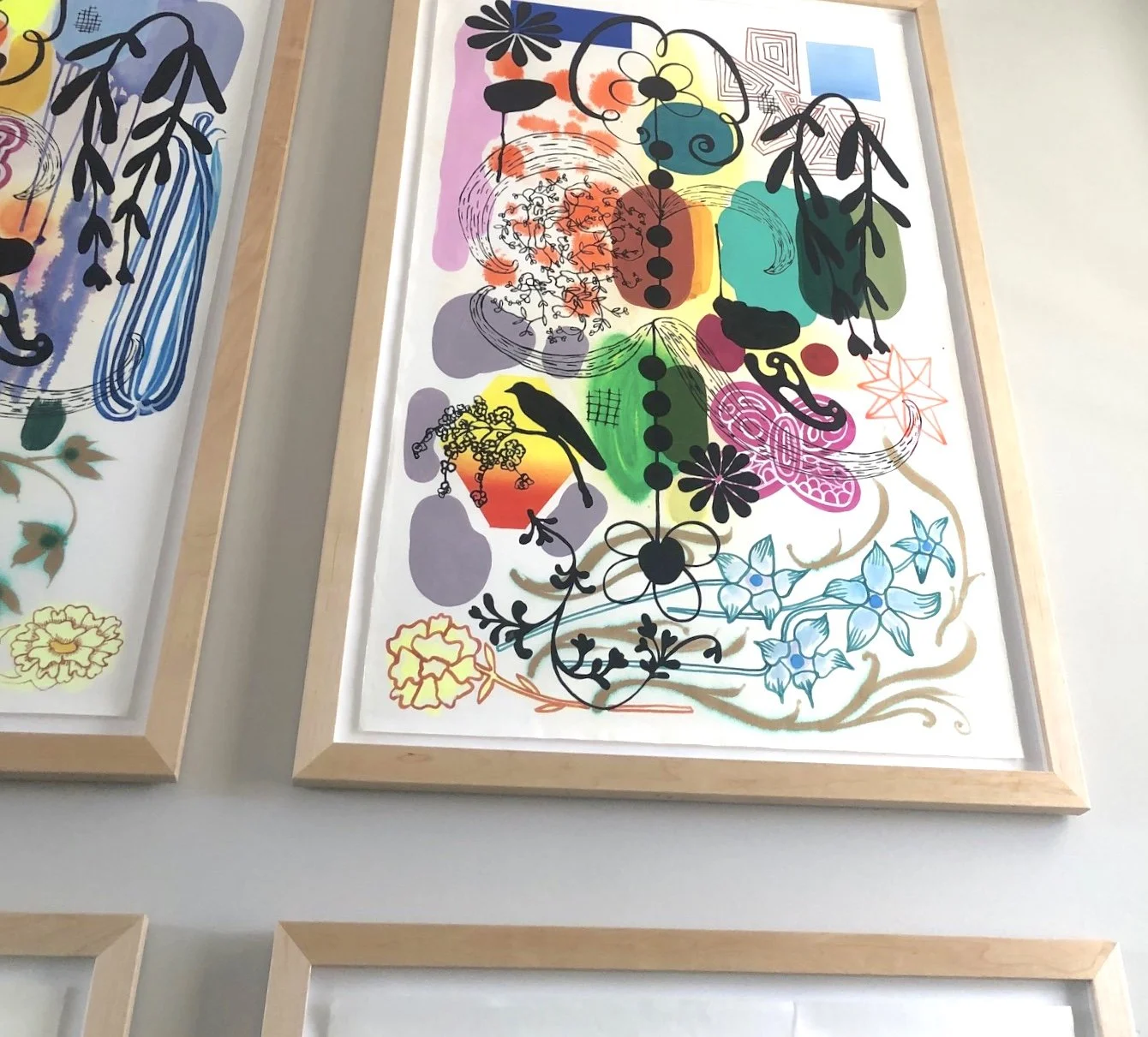 Colorful abstract floral and botanical illustration with black silhouettes of birds and various geometric shapes, framed and displayed on a wall.