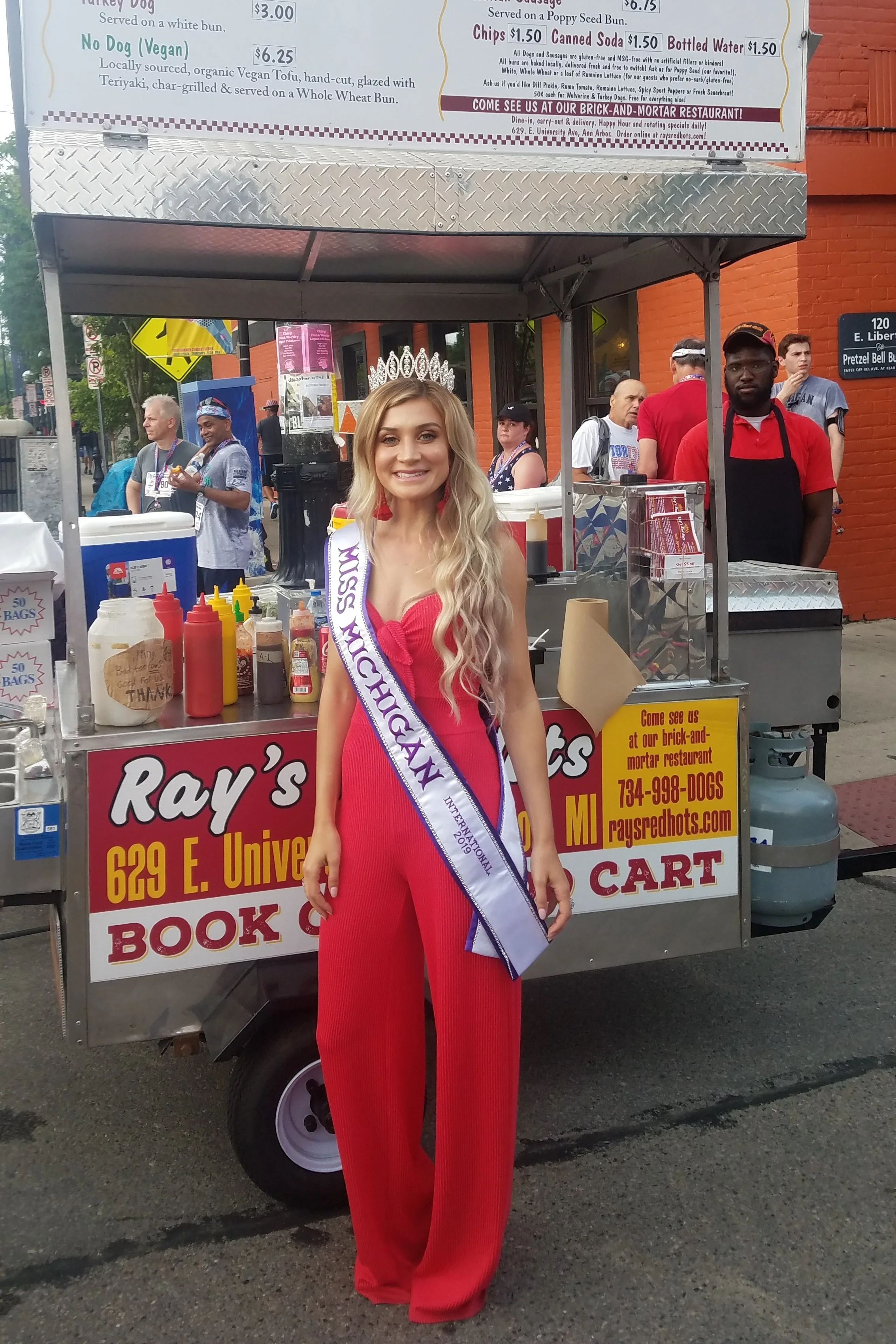 Miss Michigan International 2019 stops by to get her mom a dog at the Firecracker 5k / Fourth of July Parade in downtown Ann Arbor.