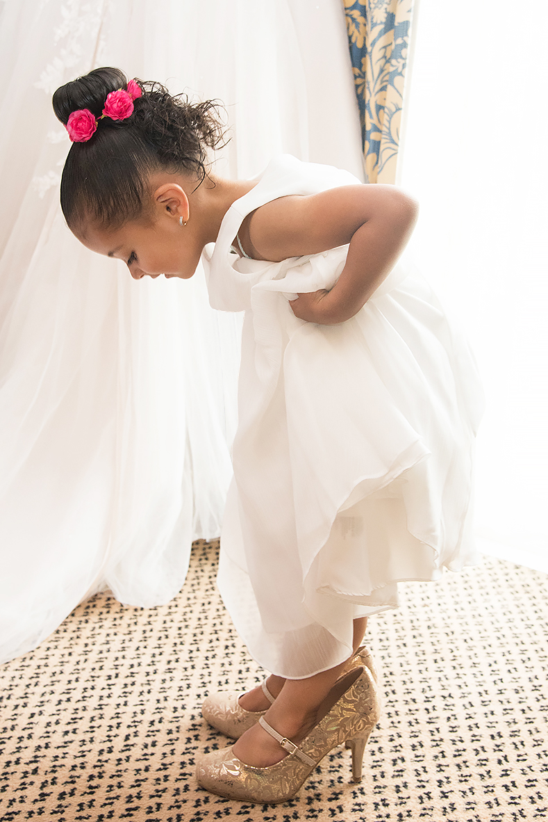 Cute flower girl trying on bride's shoes by Clickspeed Wedding Photography 