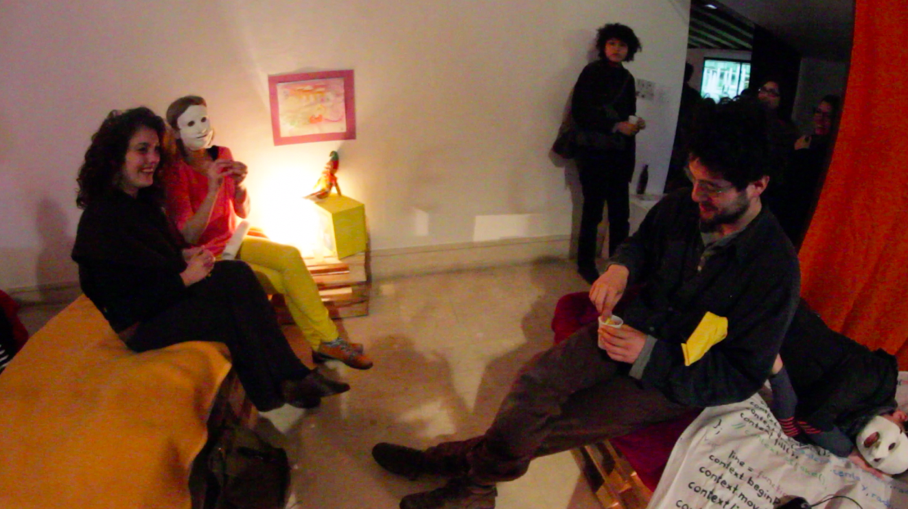 instal_flatmates_perfopening_noemimask sitting beside woman_balltossingmanscene_2014.png