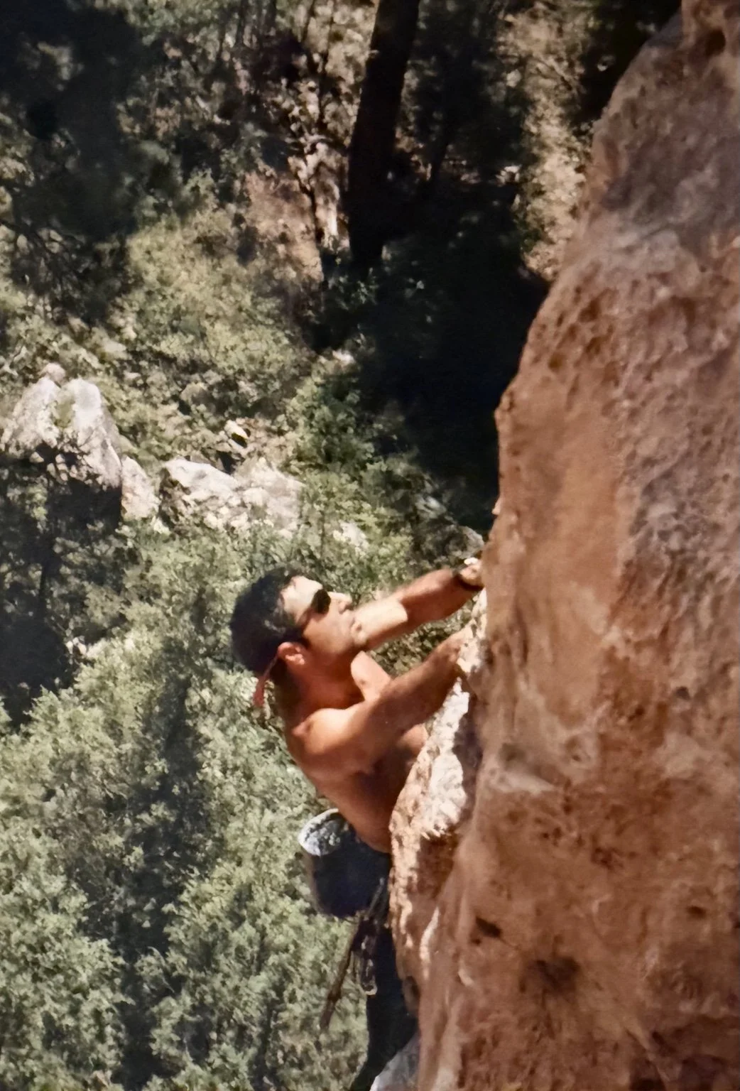 Climber reaching for a hold on a sunlit rock face.