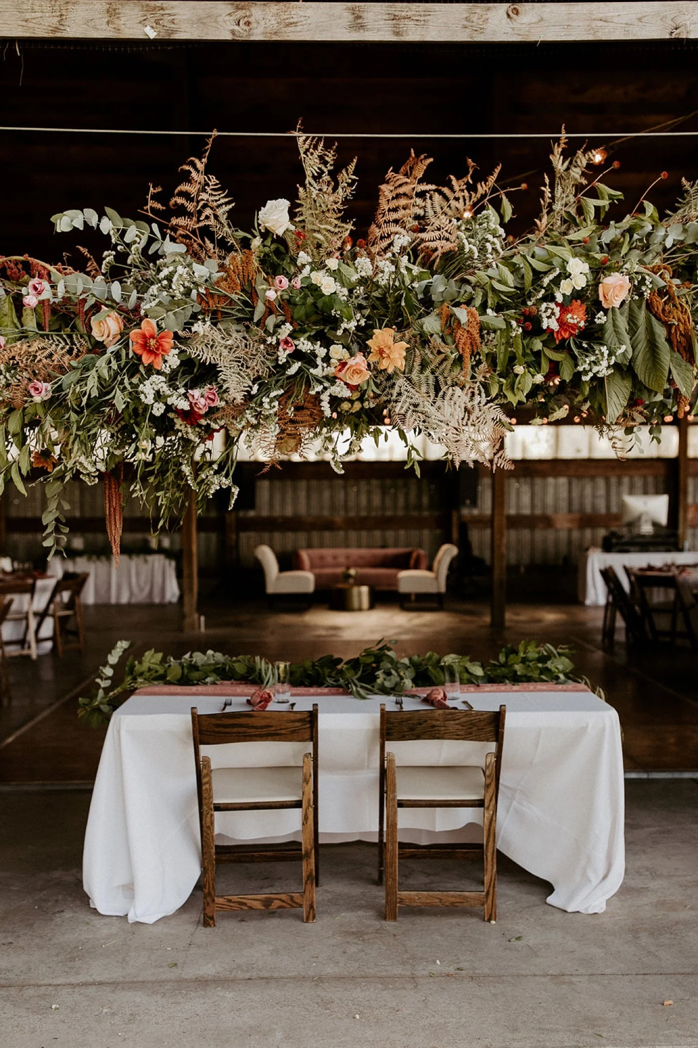 Sweetheart table floral installation with ferns, eucalyptus, and roses from Songbird Floristry