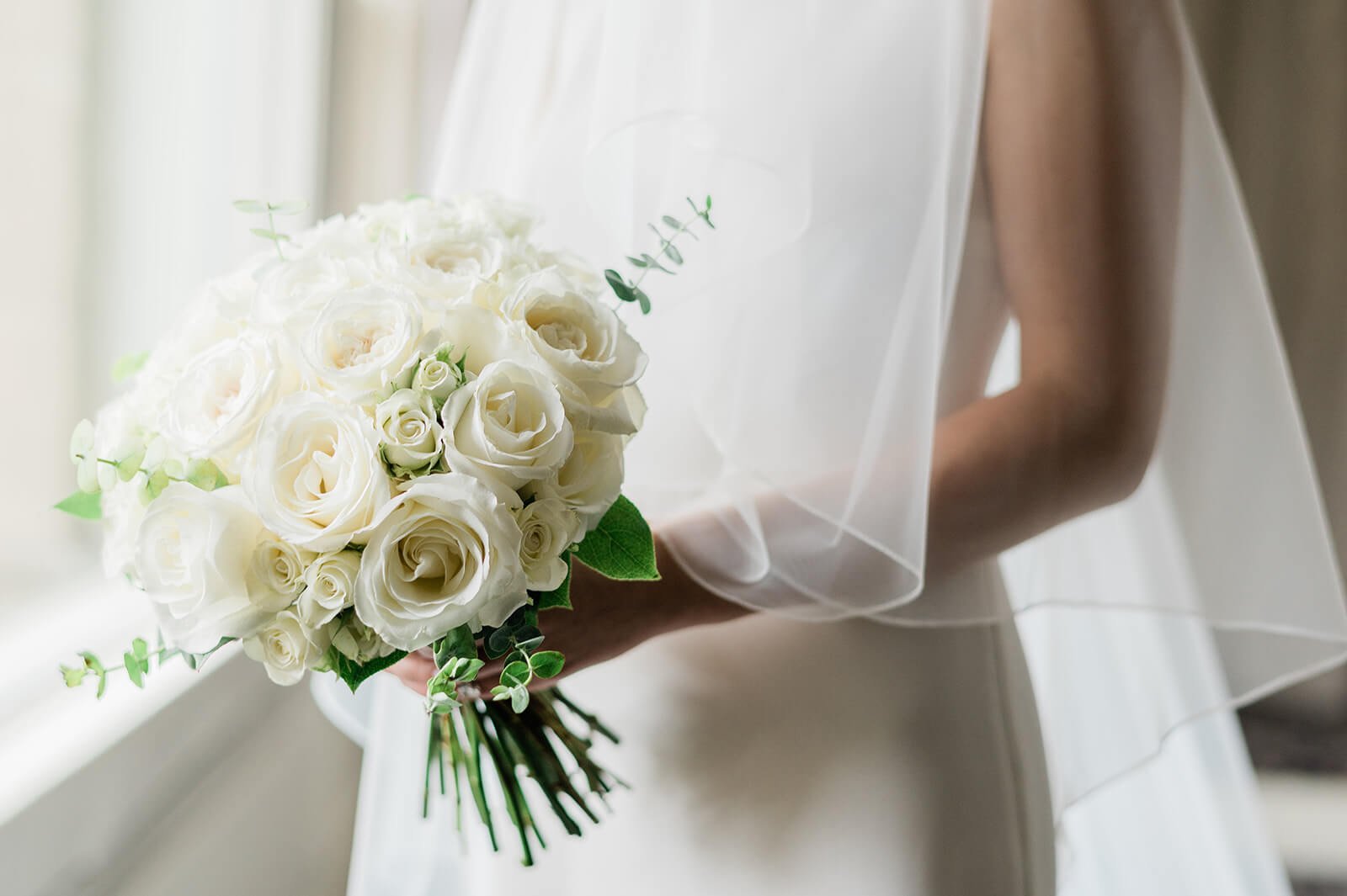 A bridal bouquet filled with ivory roses and eucalyptus by Damselfly Designs