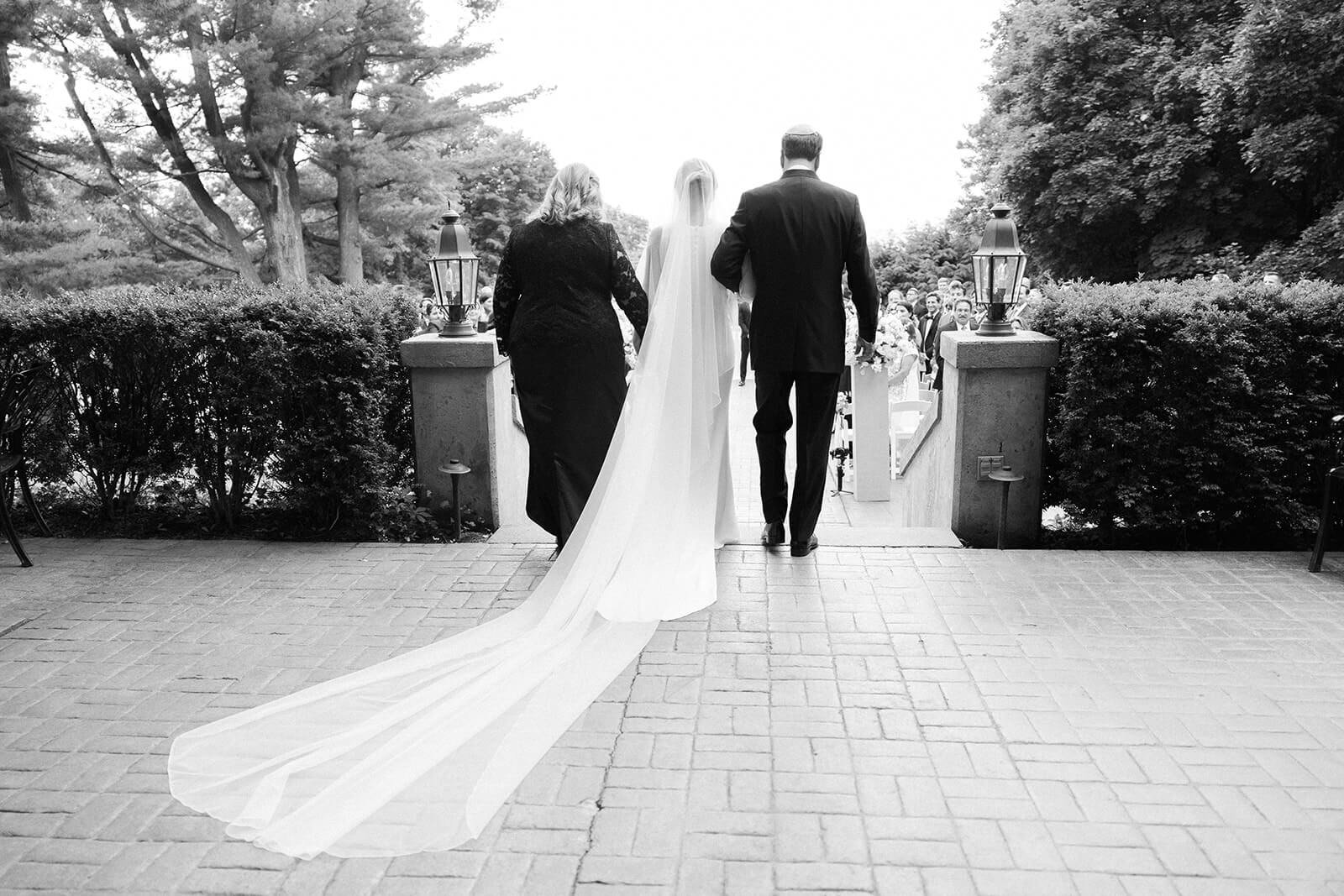 Bride walking down the aisle with her mom and dad