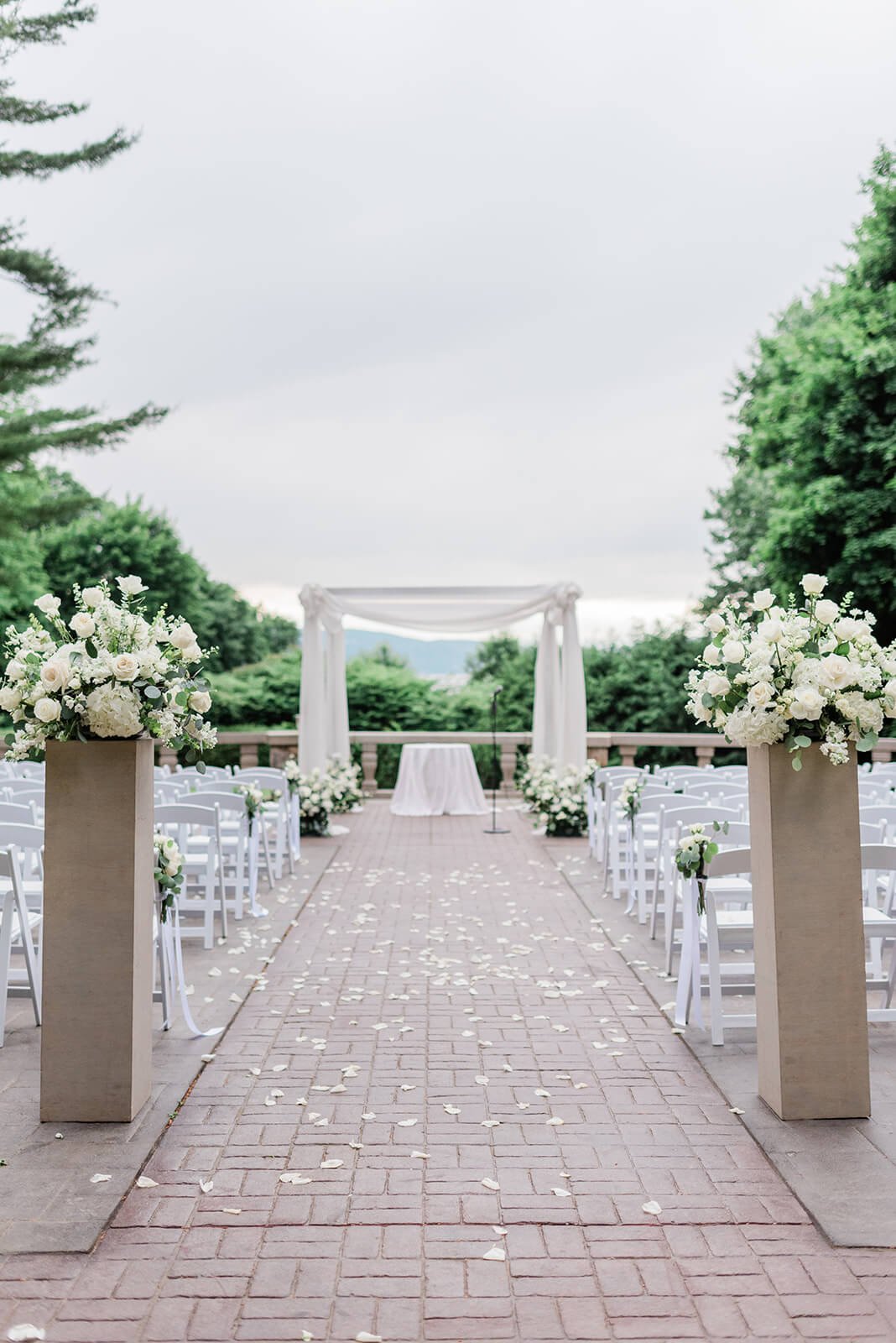 Chuppah with white drapery and white florals for an outdoor wedding ceremony