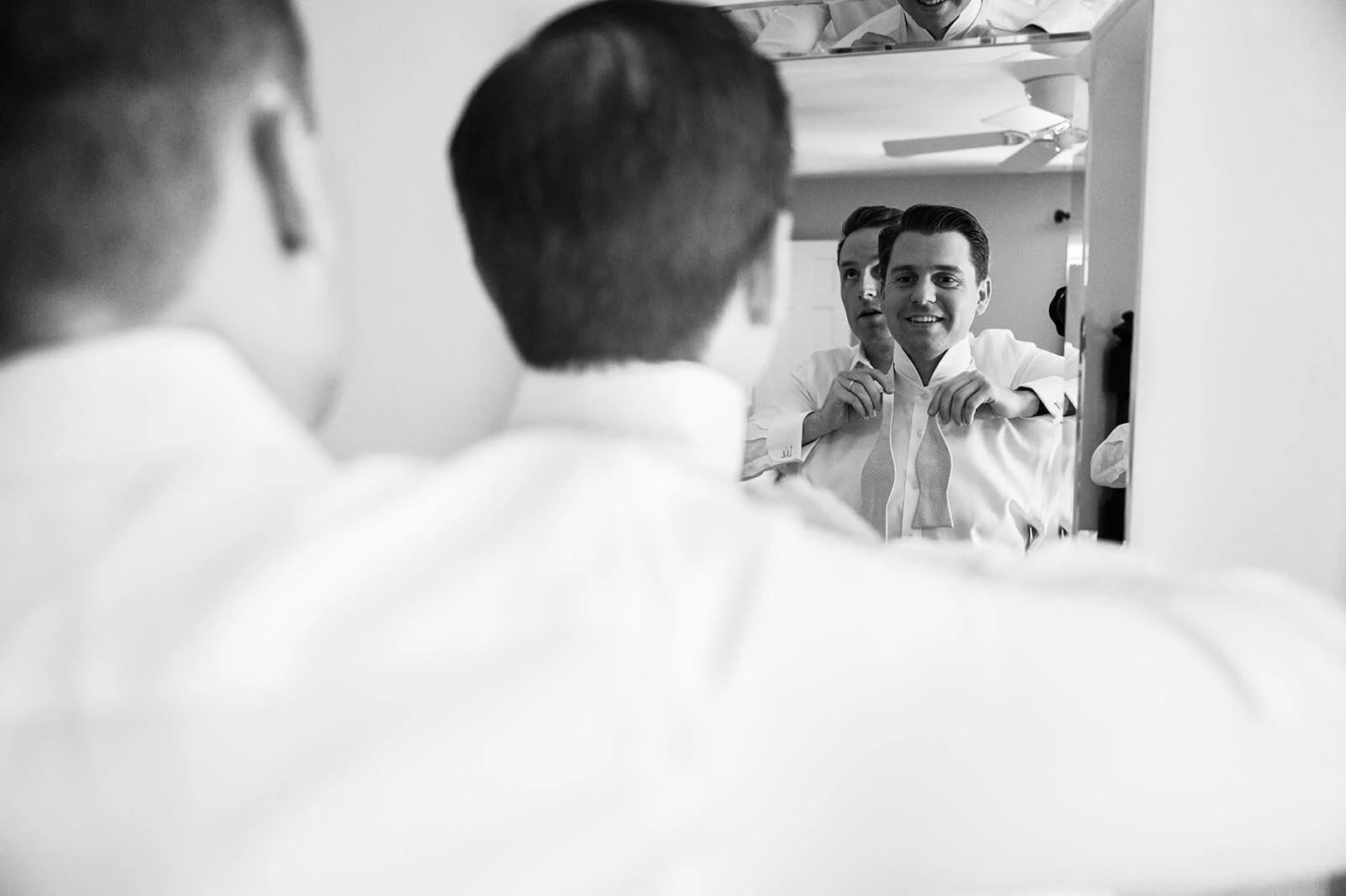 Groomsmen putting on the grooms bowtie