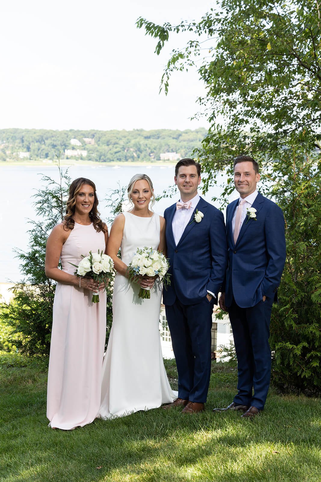 Bridal party portrait with the best man wearing a navy suit and the maid of honor wearing a blush pink gown