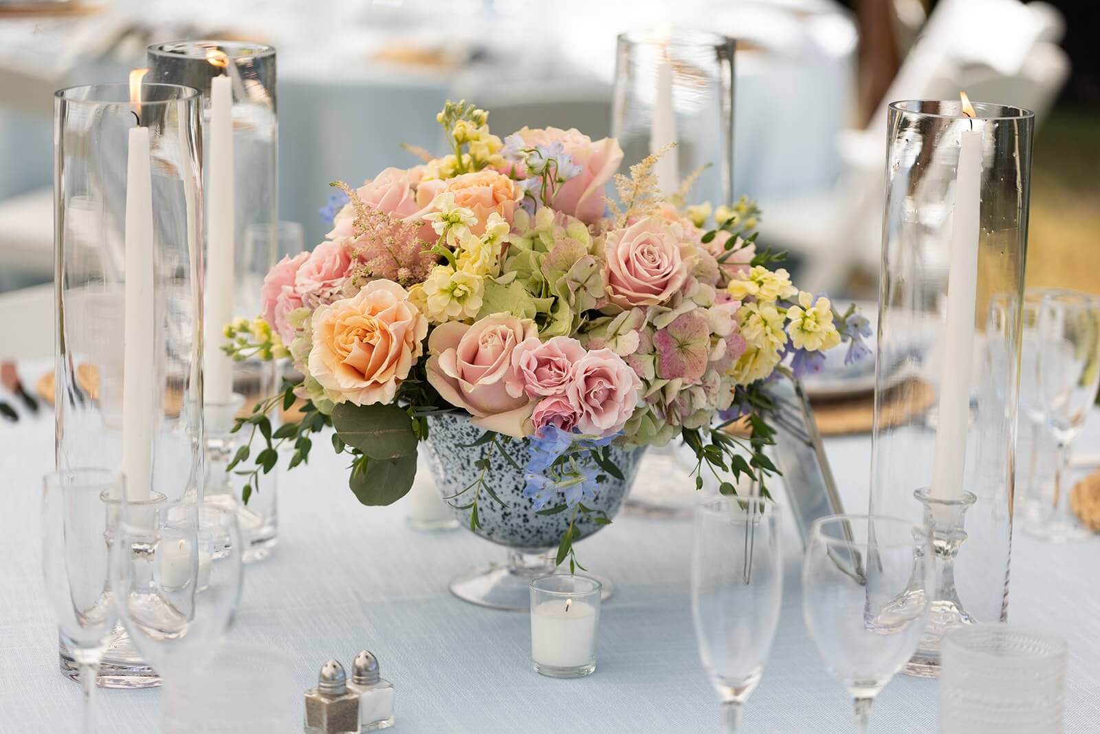 Floral centerpiece with blush roses and green hydrangeas at a summer wedding reception