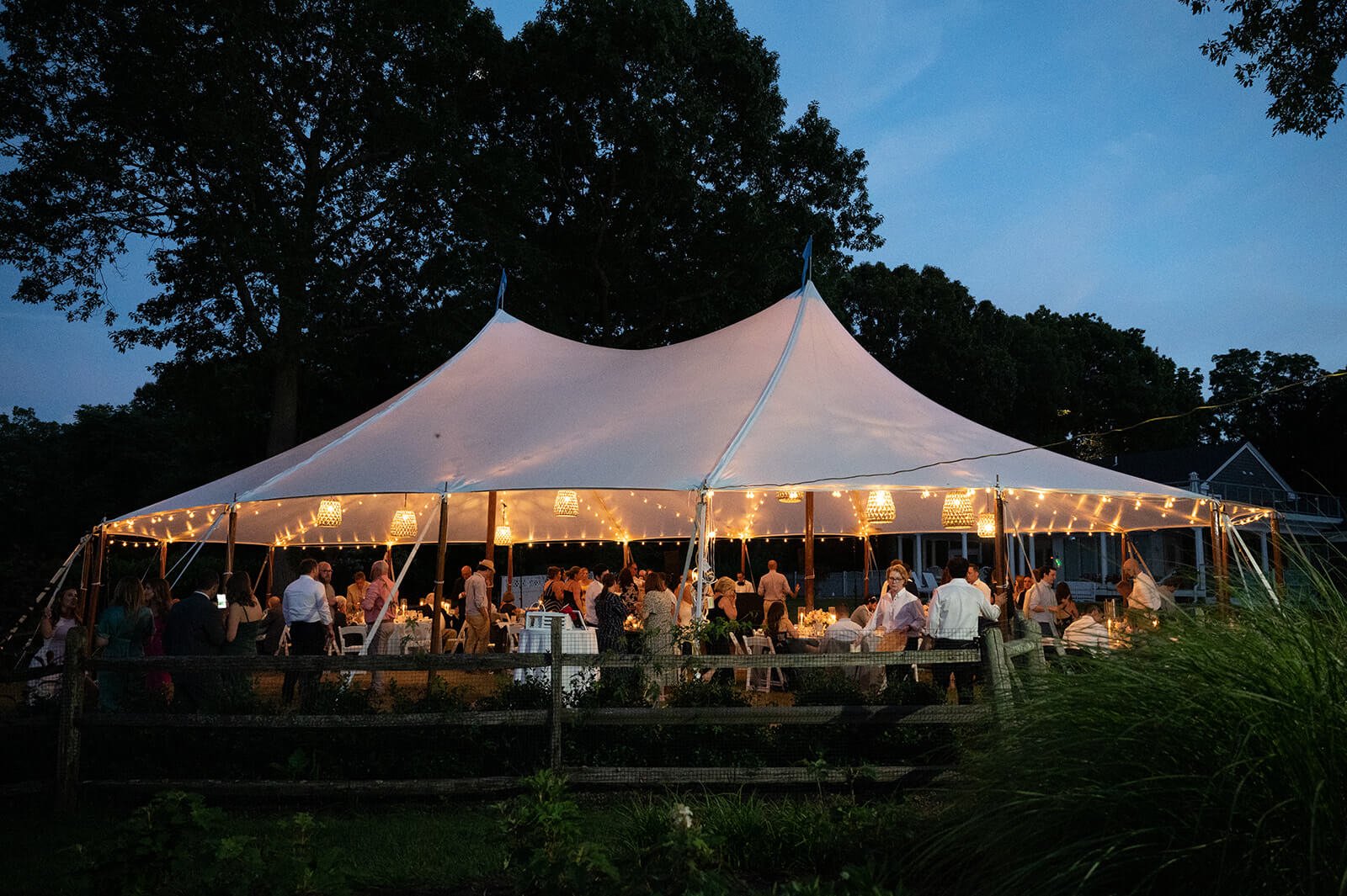 Sailcloth tent with hanging rattan lanterns at a backyard wedding in New York