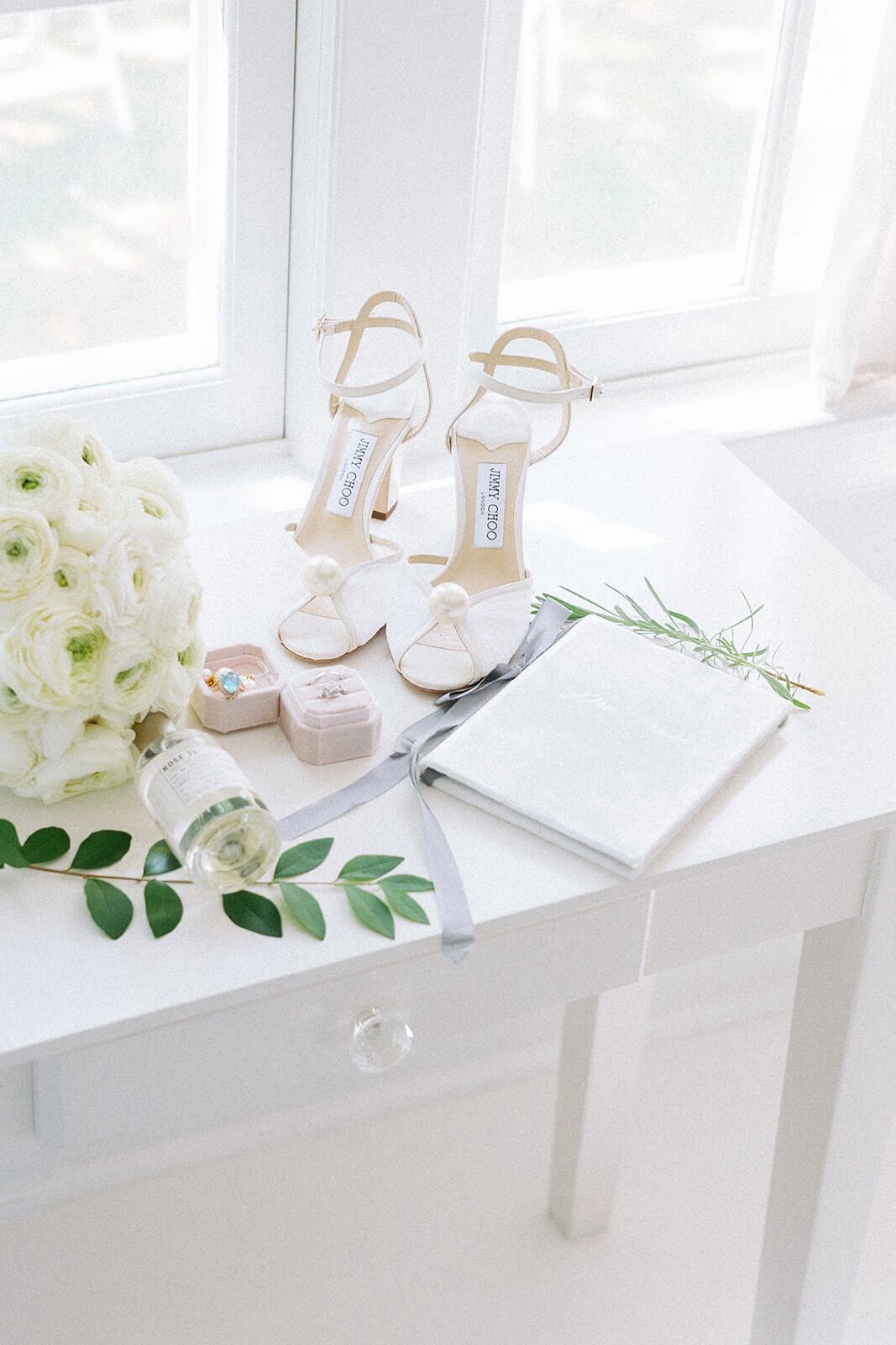 A bouquet of white garden roses with a blush velvet ring case and a pair of Jimmy Choo bridal shoes