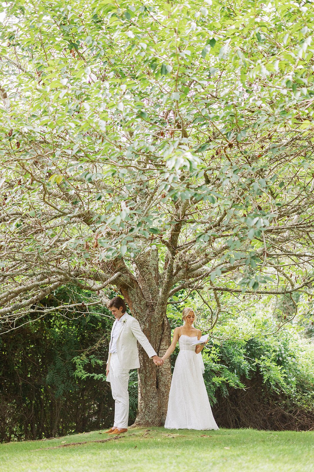 Bride and groom doing a first touch with private vows under a tree